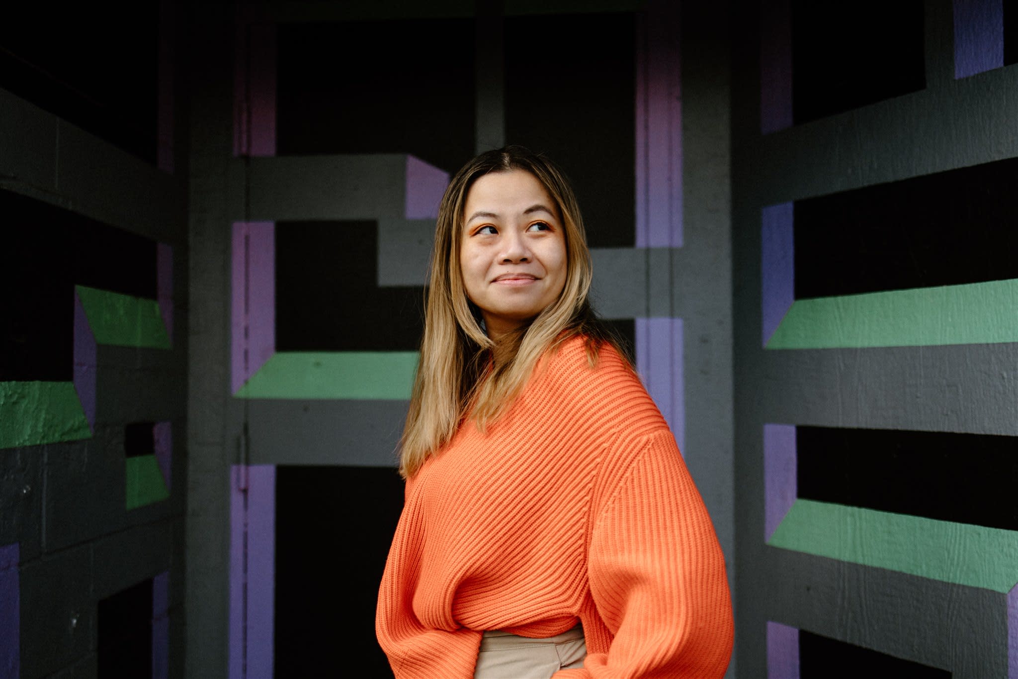 Author Tatiana smiling in front of a geometric backdrop