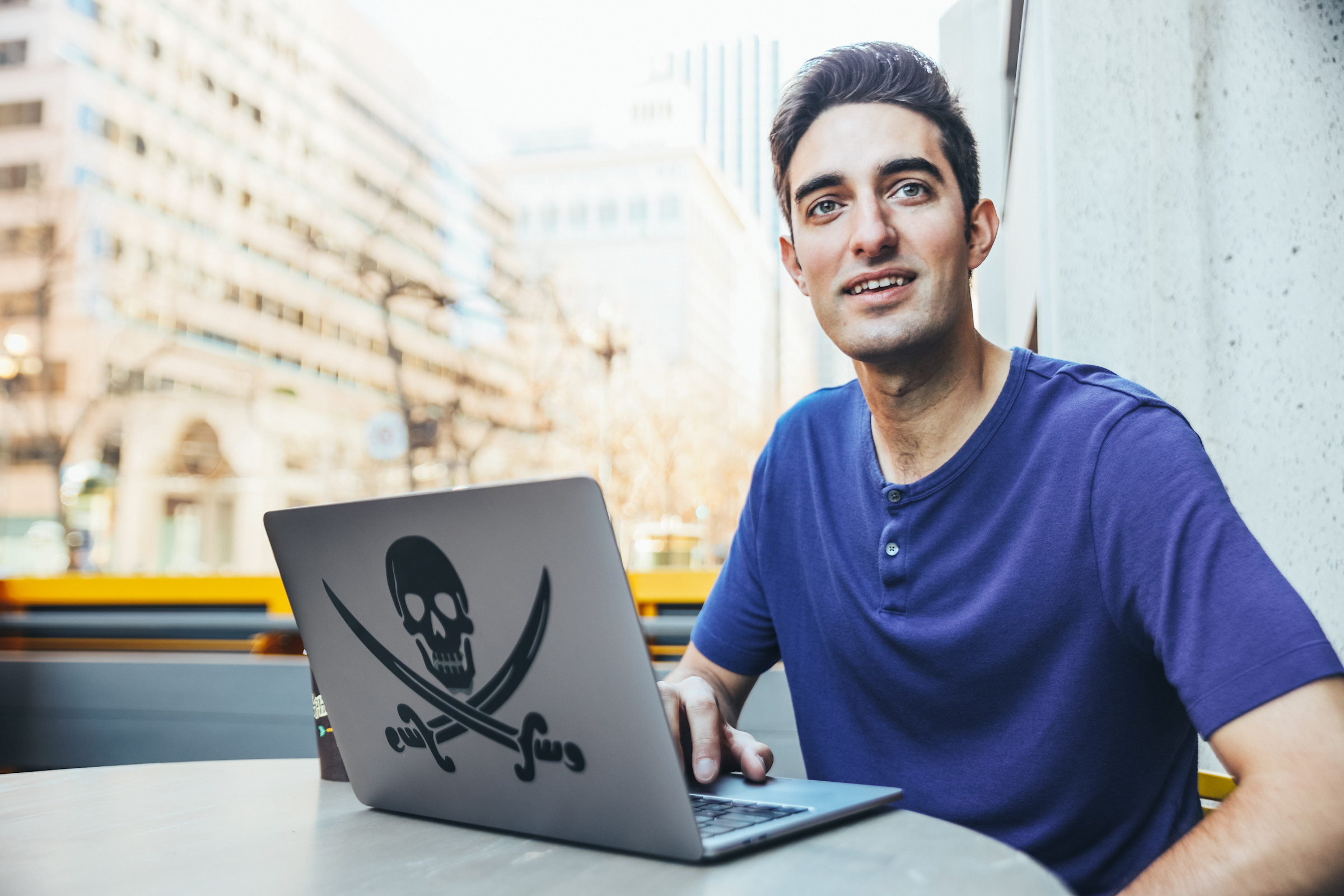 Author Feross working on his laptop at a table in an outdoor urban space