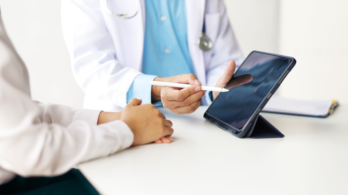 woman speaking with gastroenterologist doctor looking at iPad