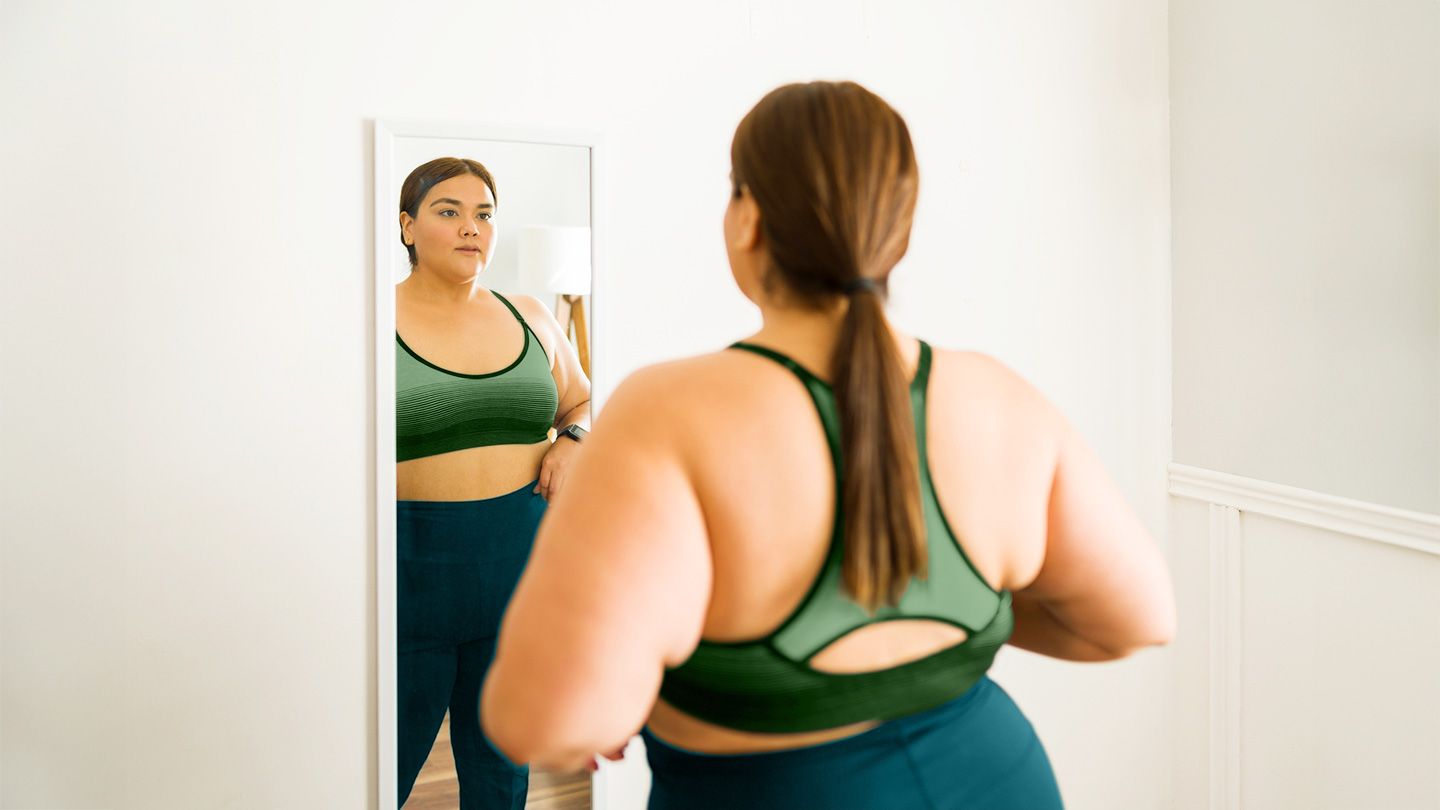 woman looking in mirror in exercise clothing