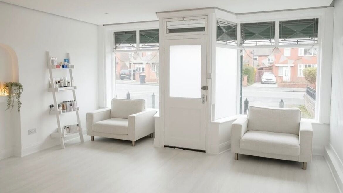 Bright, welcoming lounge at Bare Skin Clinic, Worsley, England, GB with white sofas and natural light.