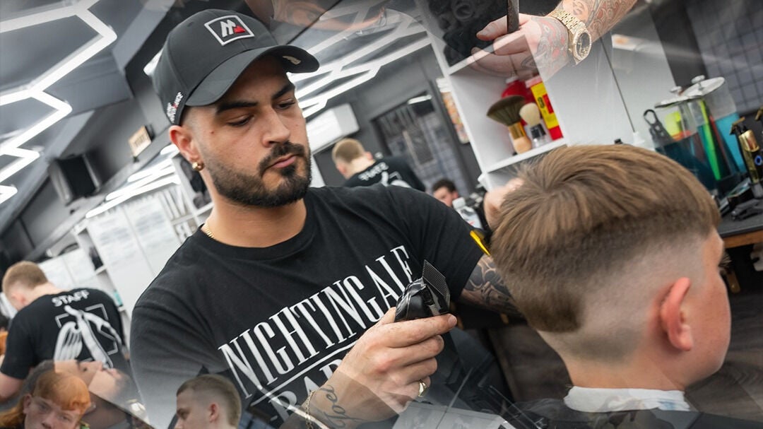 Barber at Nightingale Barbers in Oxenford, Queensland, AU styling a client's hair with precision.