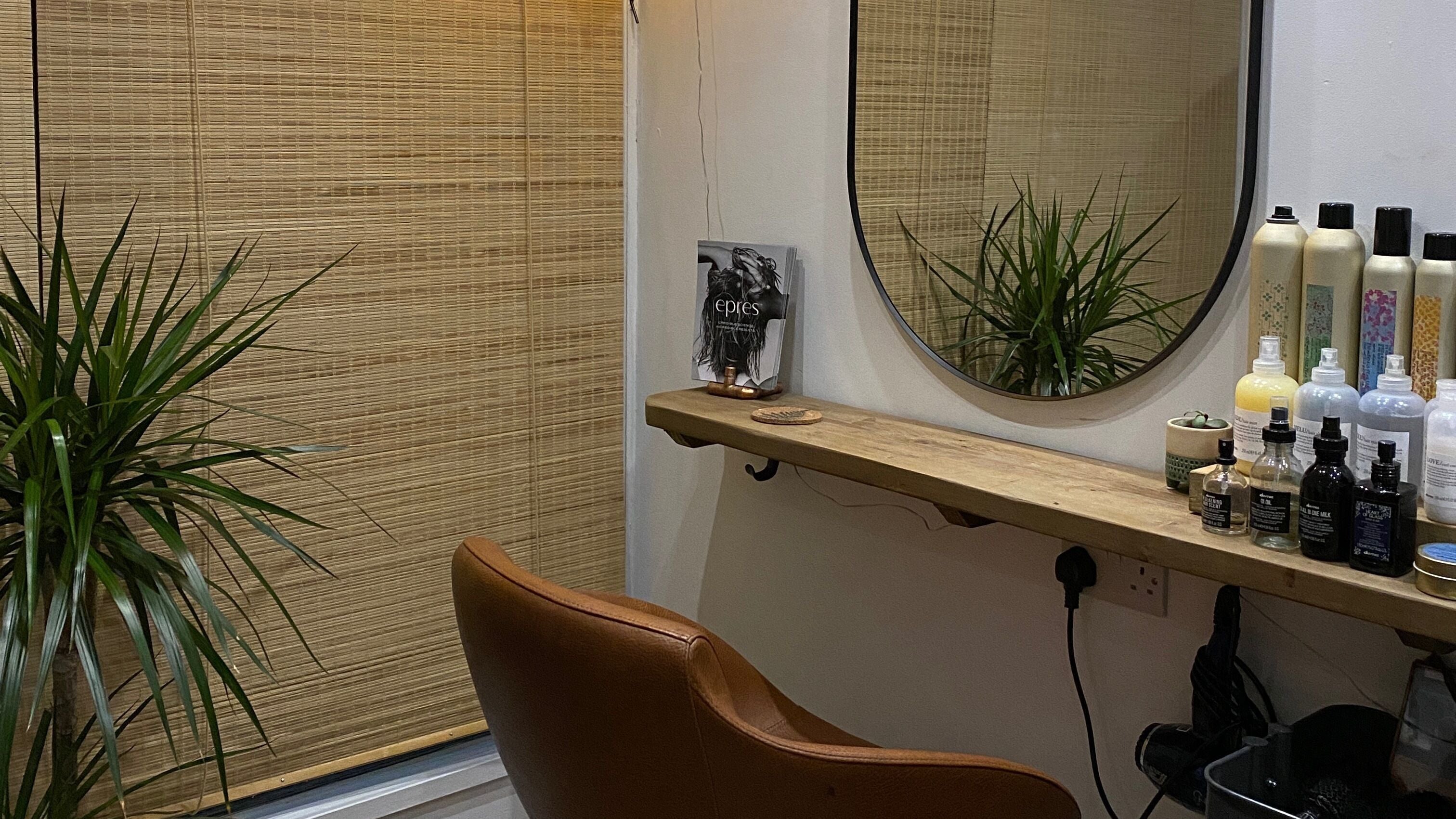 Elegant styling station at Fern Hair Studio, Exeter, England, GB with mirror, products, and leafy plant for a welcoming vibe.