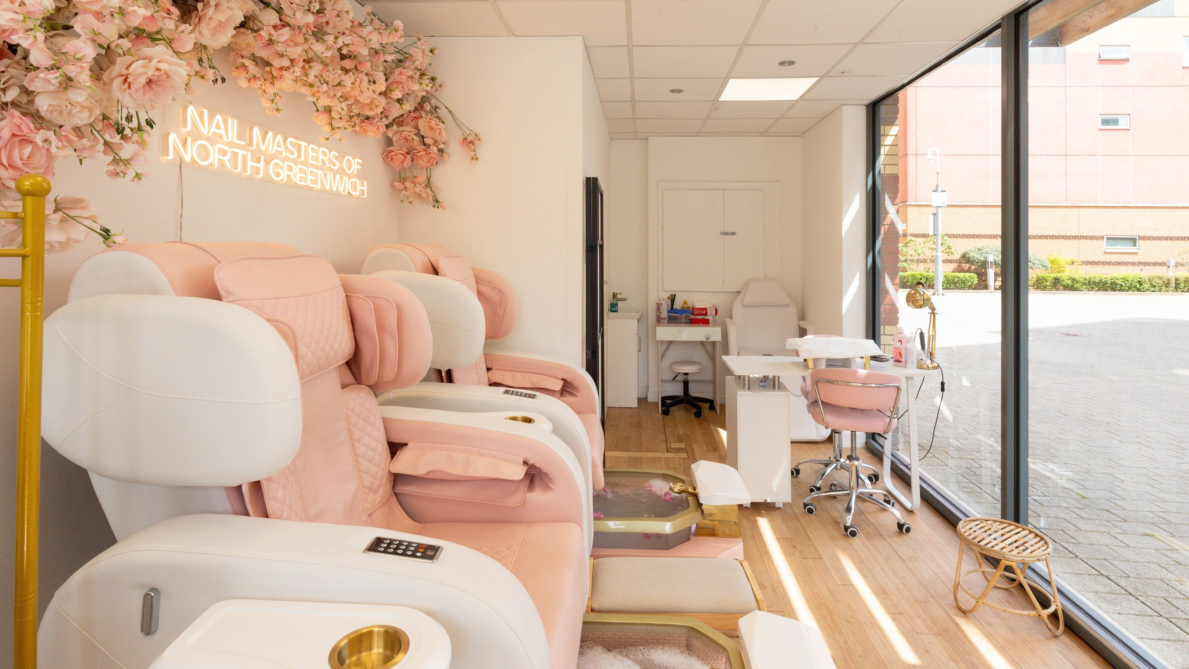 Interior of Nail Masters of North Greenwich, London, England, GB. Luxurious pink chairs and floral decor.