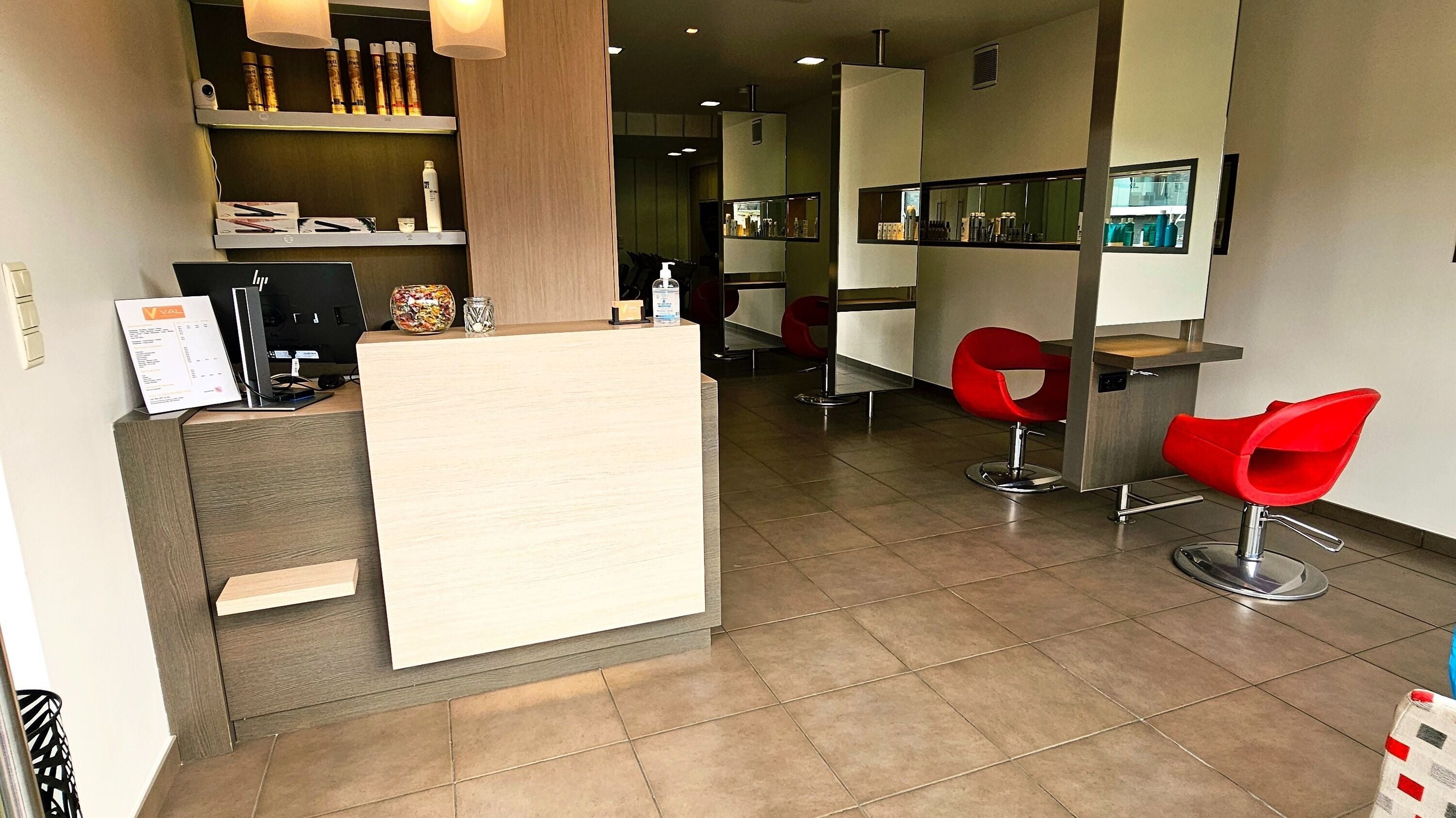 Intérieur moderne du salon de coiffure VAL Hairdresser à Overijse, Vlaams Gewest, BE, avec chaises rouges élégantes.
