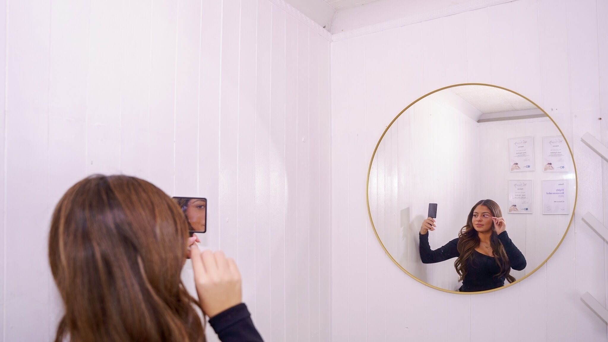 A woman checking her makeup in a circular mirror at AZ BEAUTY MK, Fishermead, England, GB.