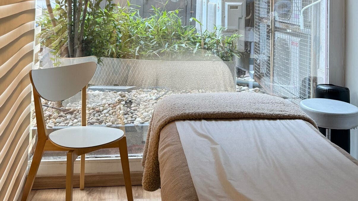 Cozy treatment room at ÓG Esthetics & Health, Lisboa, Lisboa, PT, overlooking a lush garden through glass walls.