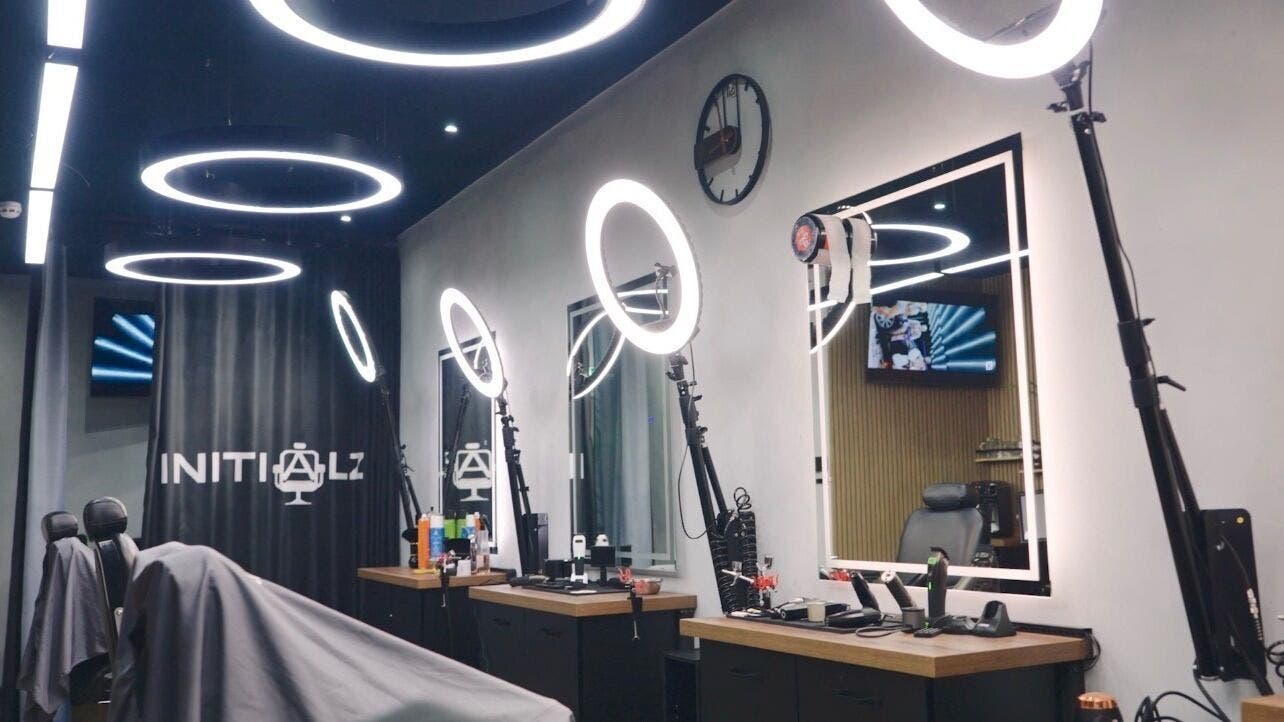 Modern barbershop interior at Initialz Barbers, London, England, GB featuring sleek chairs and advanced LED lighting.