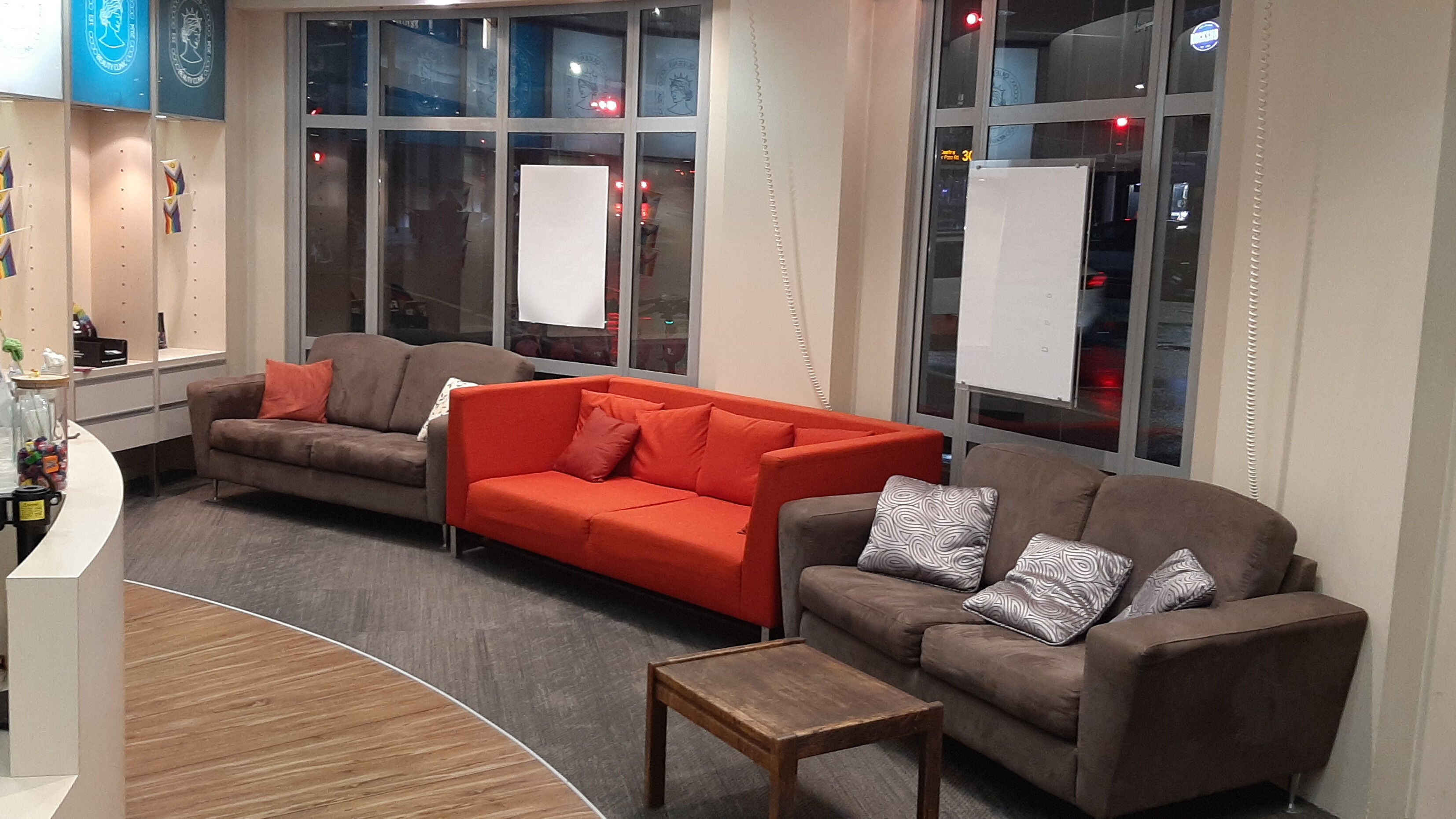 Comfortable lounge area at Queens Beauty Clinic, Auckland, NZ with modern sofas and ambient lighting.