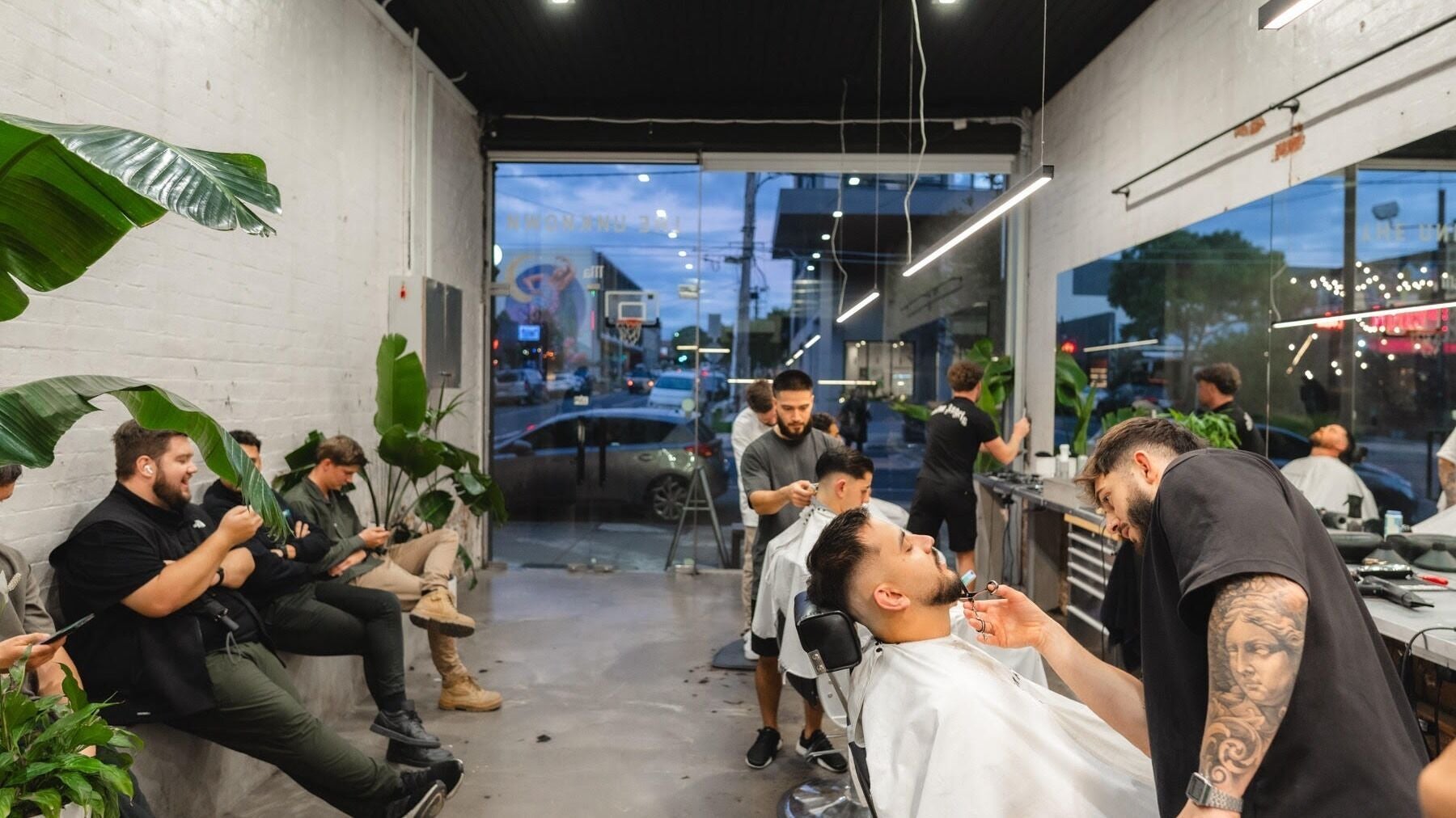 Modern interior of The Unknown Barbers - Preston in Melbourne, Victoria, AU with clients receiving haircuts.