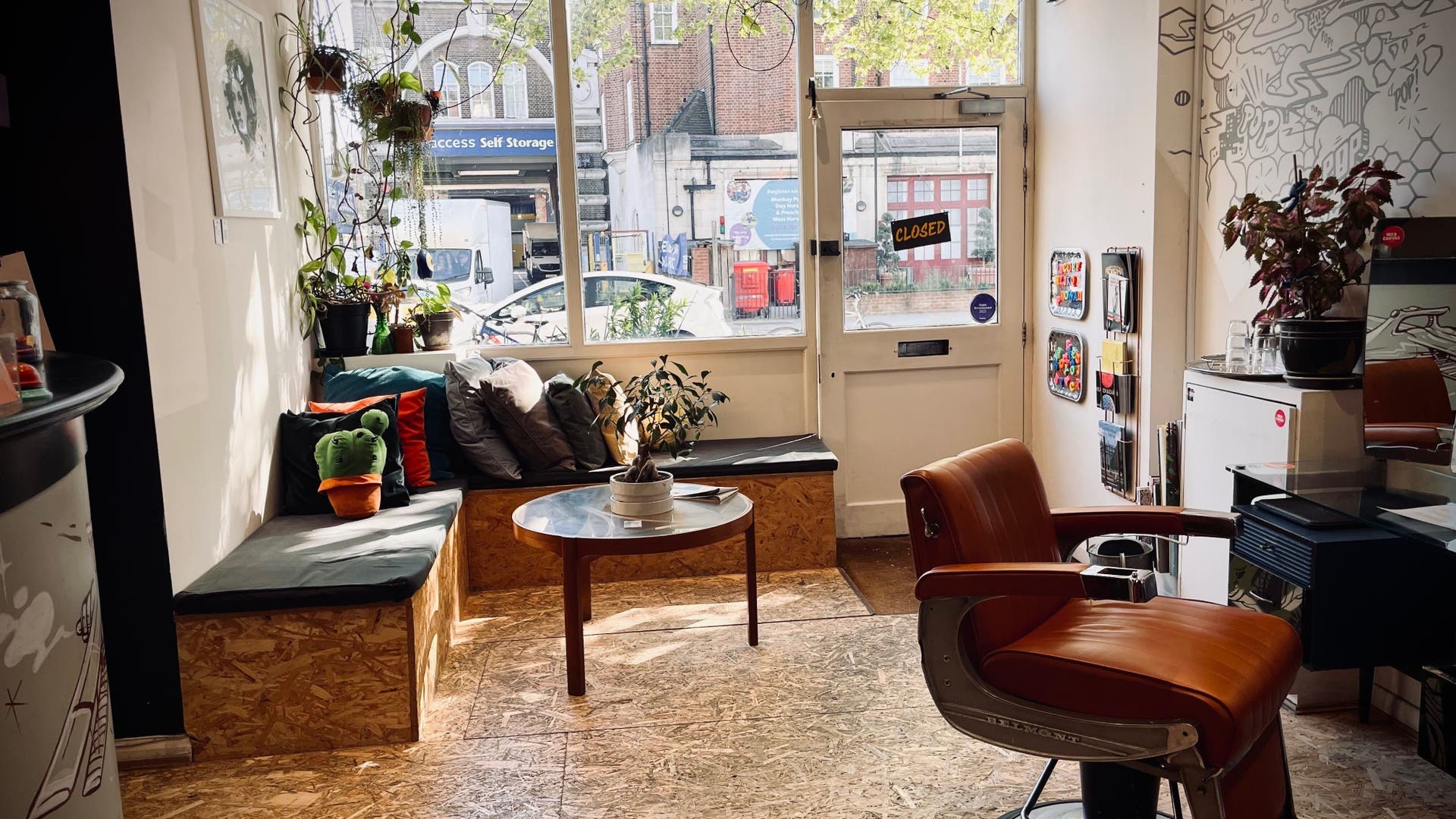 Bright, cozy seating area in POP West Norwood salon, London, with plants and cushions.