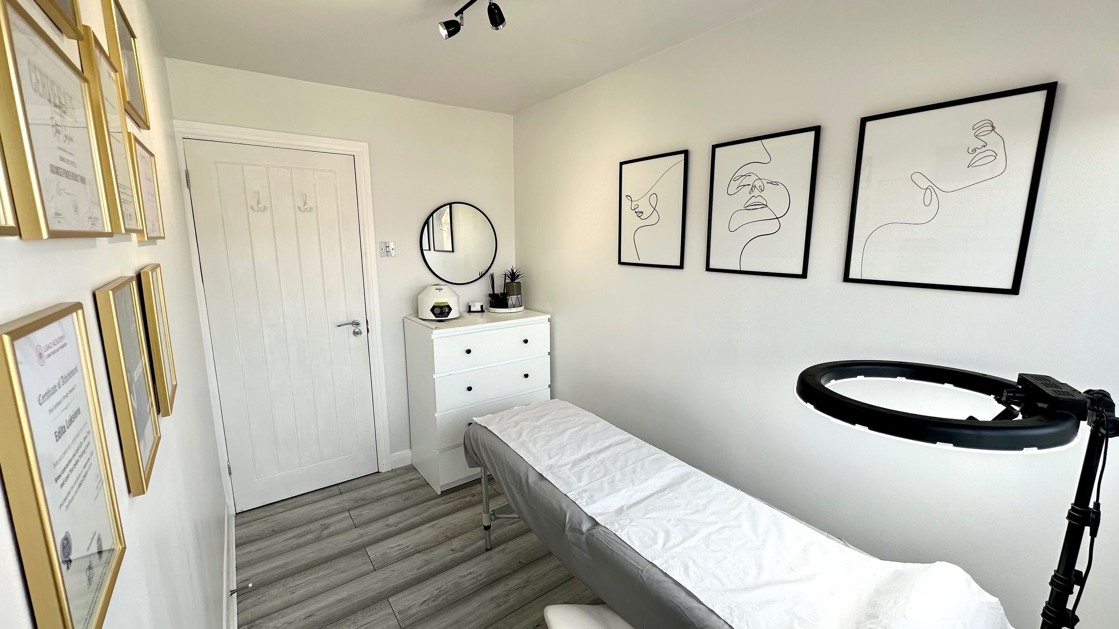 Edi Beauty & Aesthetics in Linford, England, GB. Minimalist treatment room with chic decor and certificates displayed.