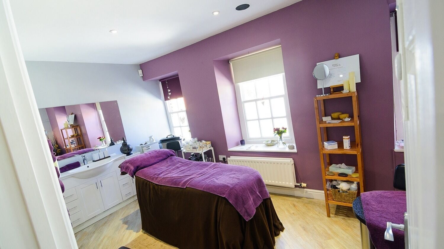 Relaxing treatment room at Pure Touch Cockermouth, Cockermouth, England, GB with purple decor and massage bed.