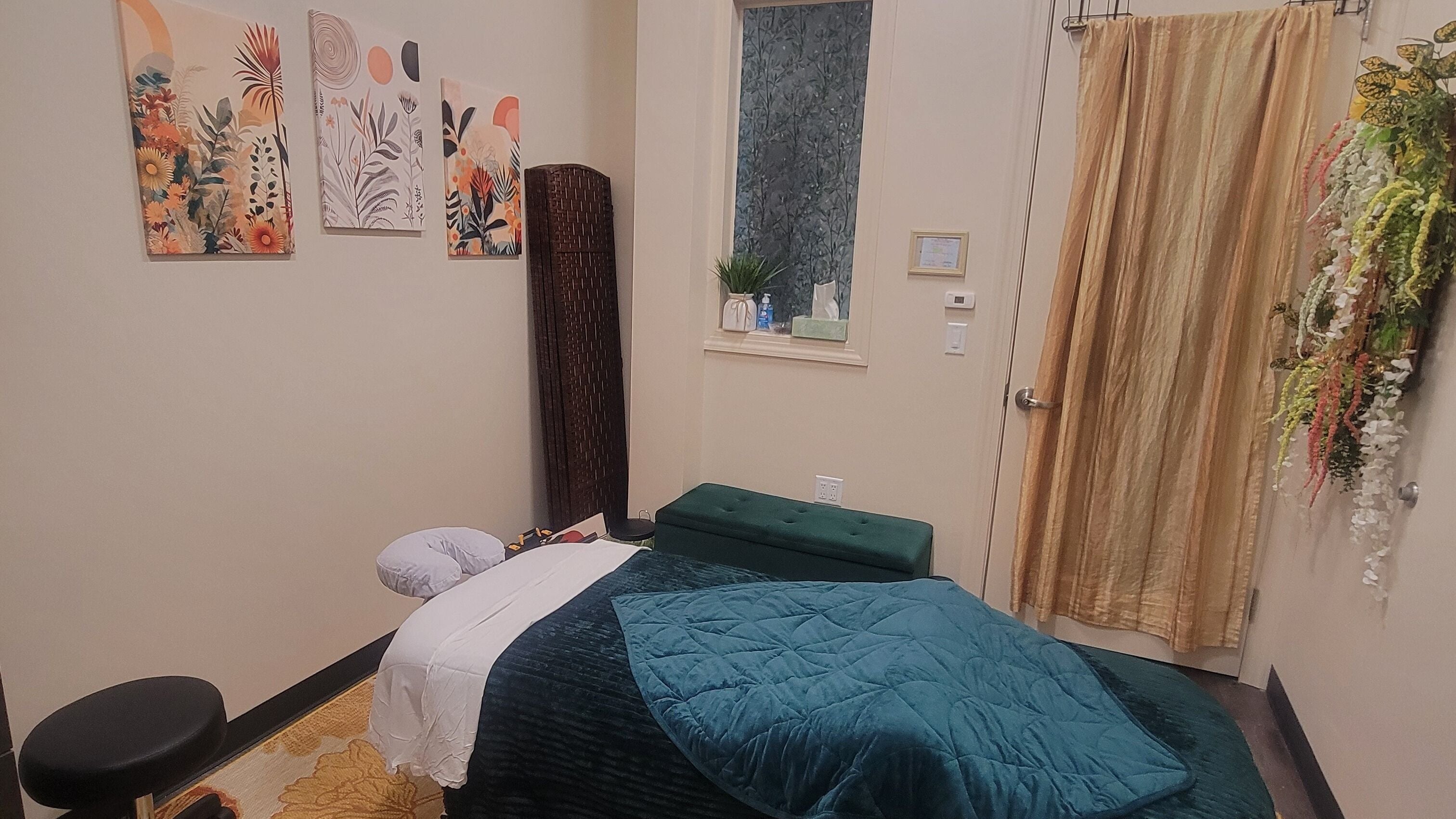 Tranquil massage room at Taylored Spa and Massage, Bayonne, New Jersey, US, featuring cozy decor and greenery.
