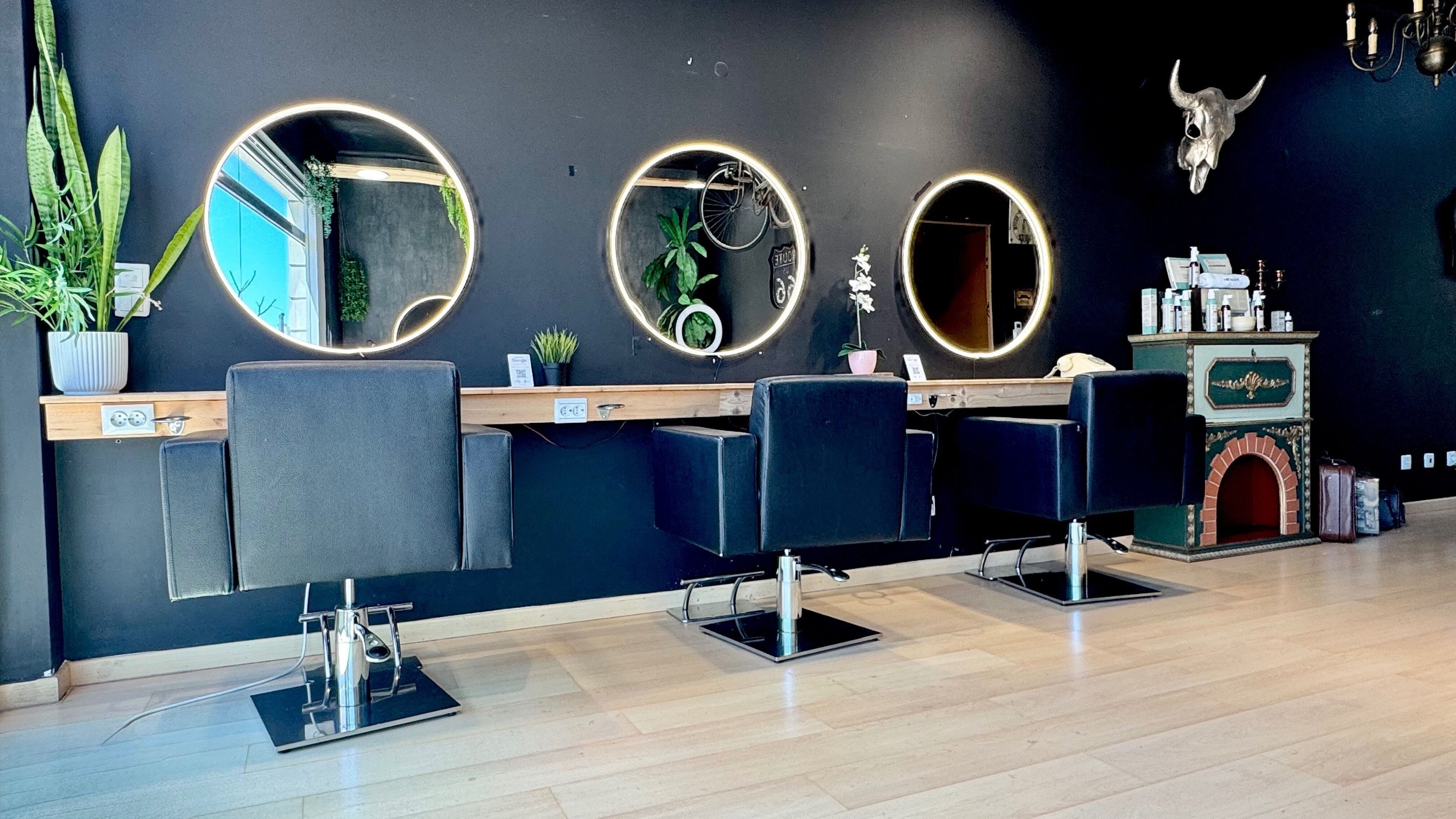 Interior moderno do New Soul Hair Studio em Póvoa de Santa Iria, Lisboa, PT com espelhos circulares e cadeiras pretas.