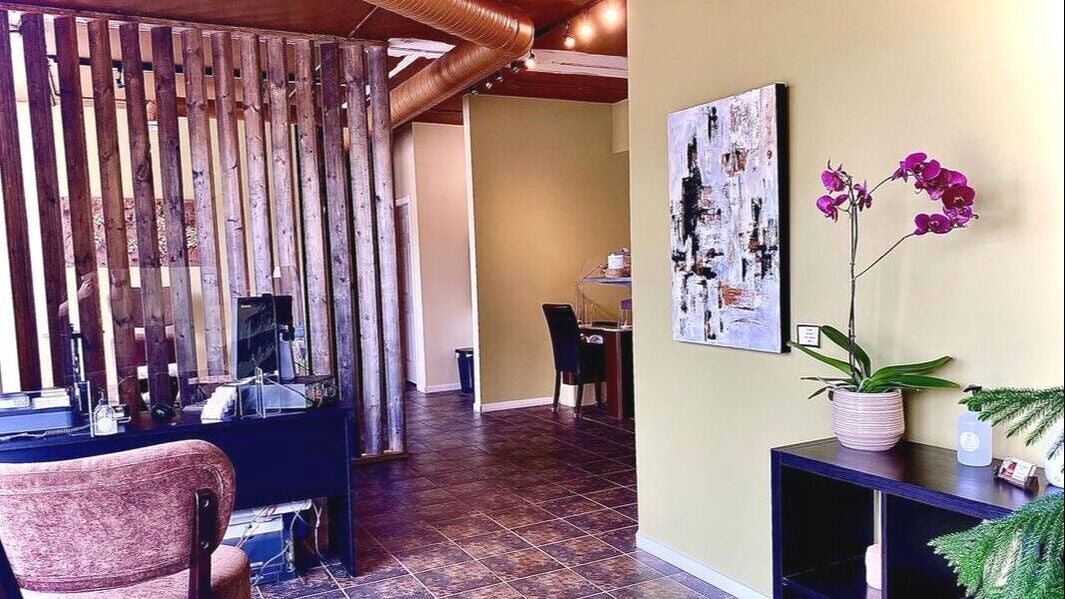 Cozy interior of Talking Tree Spa in Kelowna, BC. Features a chair, desk, and vibrant orchid decor.