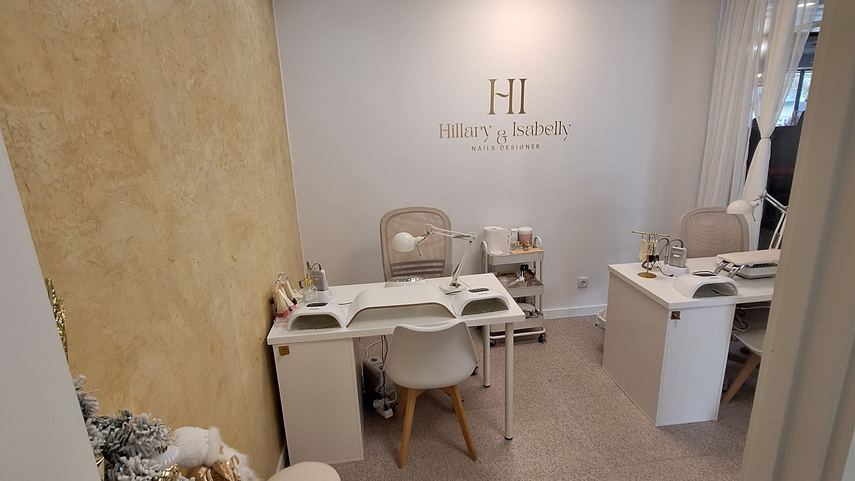 Interior do salão Hillary & Isabelly em Almada, Setúbal, PT, com mesas de manicure e decoração elegante.