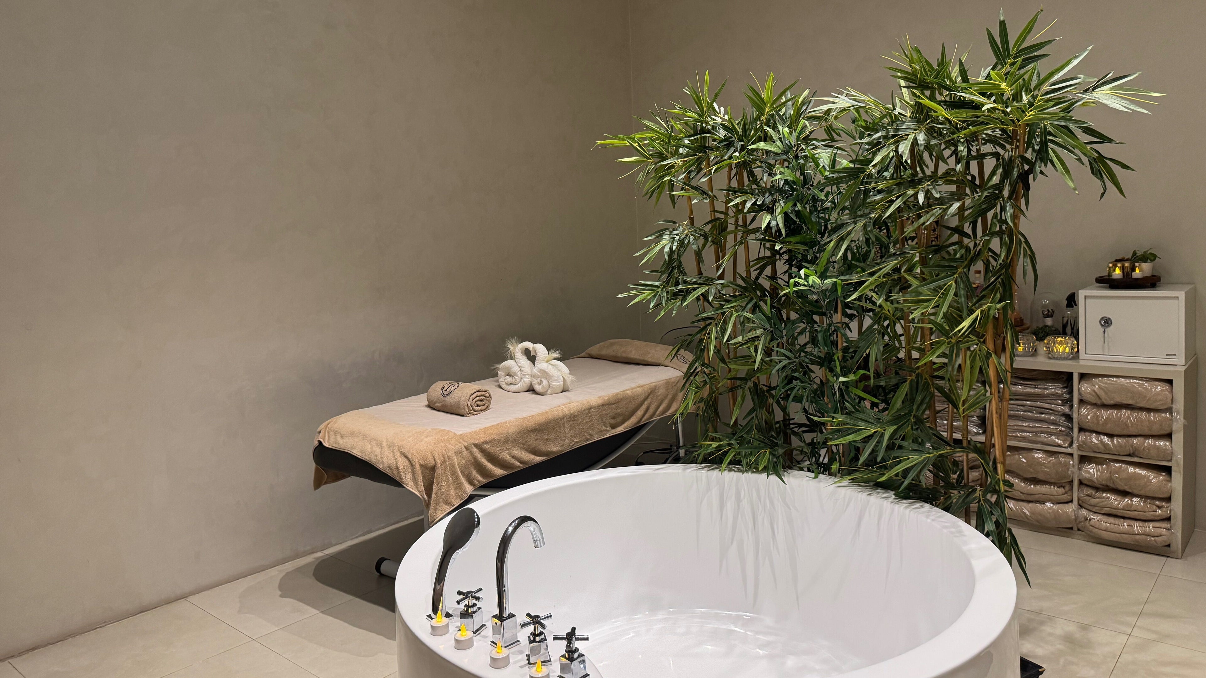 Relaxing spa room at Le Beautique Beauty & Spa لي بيوتيك سبا, Abu Dhabi أبوظبي, AE with massage bed and tub.