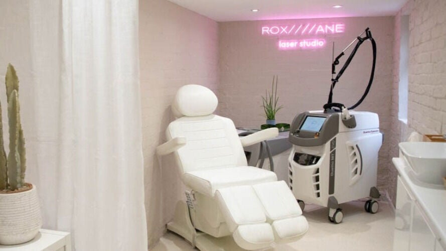 Modern laser treatment room at Roxane Laser Studio, London, England, GB, with sleek equipment and comfortable seating.