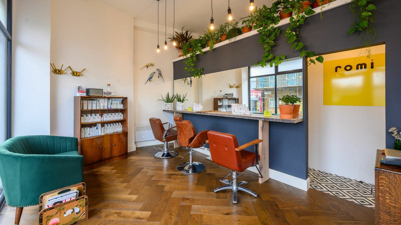 Stylish interior of Romi Salon, London, England, GB, featuring elegant chairs and vibrant decor with plants.
