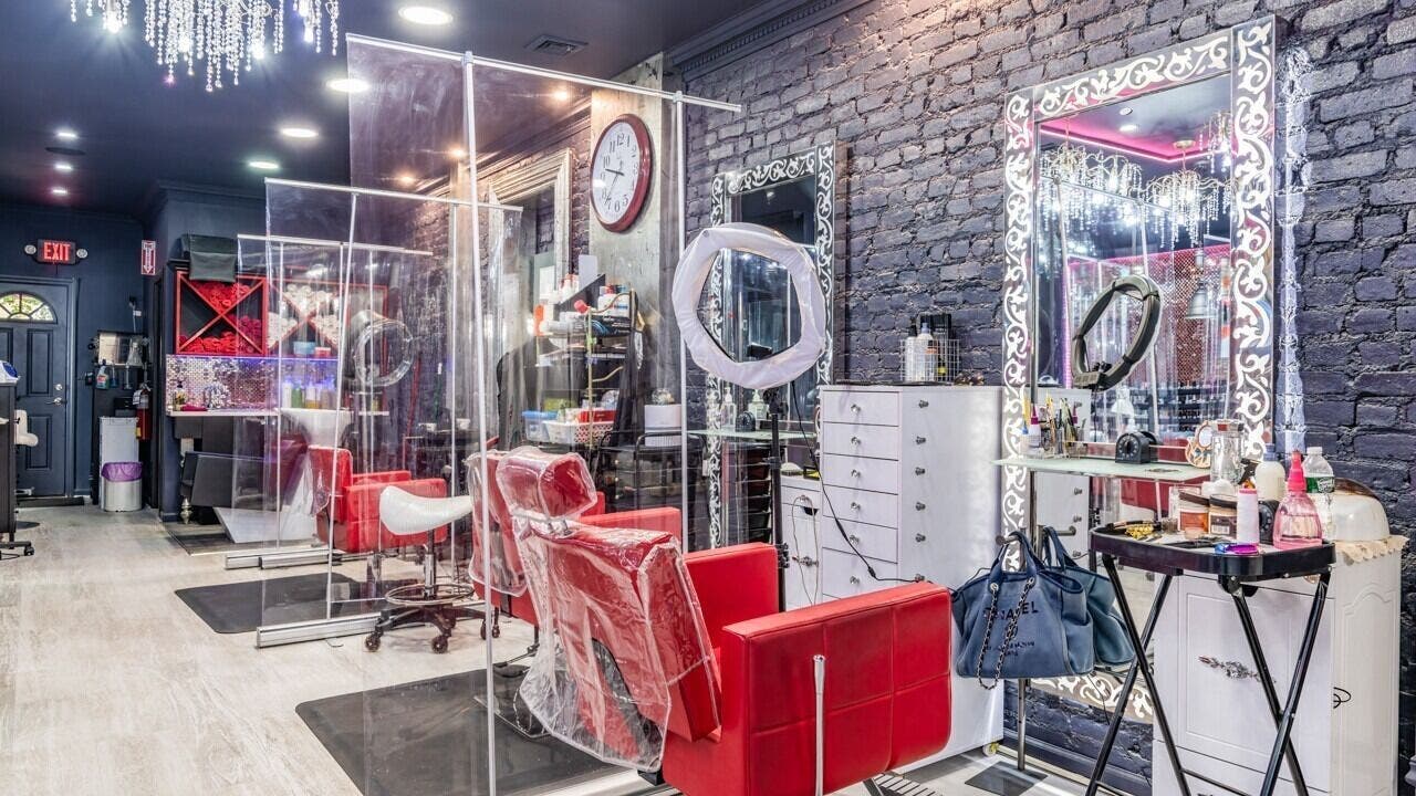 Stylish interior of Brooklyn Beauty Lounge in New York, US showcasing red chairs and ornate mirrors.