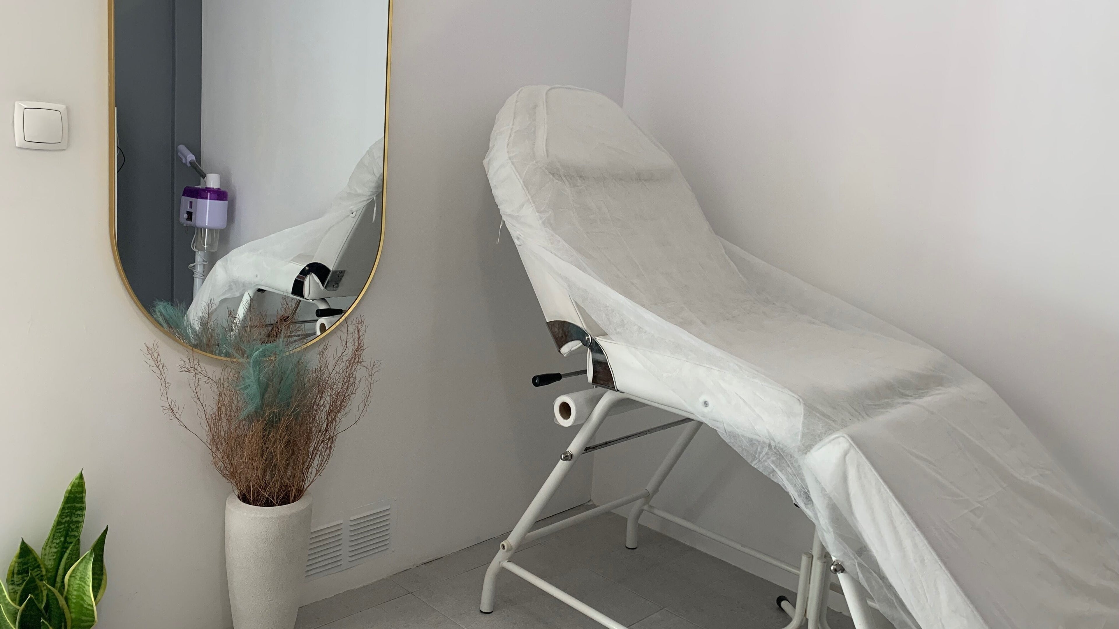 Sala de estética moderna em Nei Oliver Esteticista, Almada, Setúbal, PT, com cama de tratamento e espelho elegante.