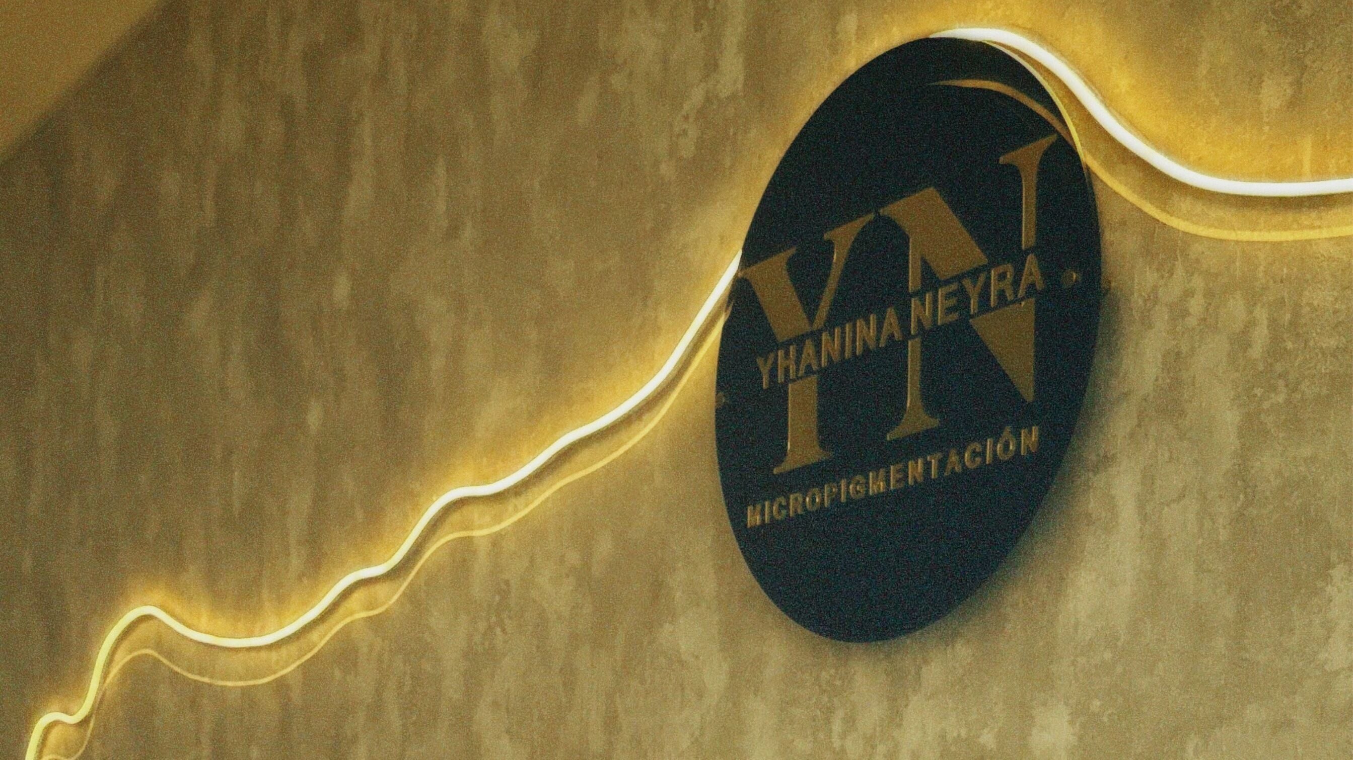 Logotipo iluminado de Yhanina Studio en Vitoria-gasteiz, Euskadi, ES en una pared texturizada.