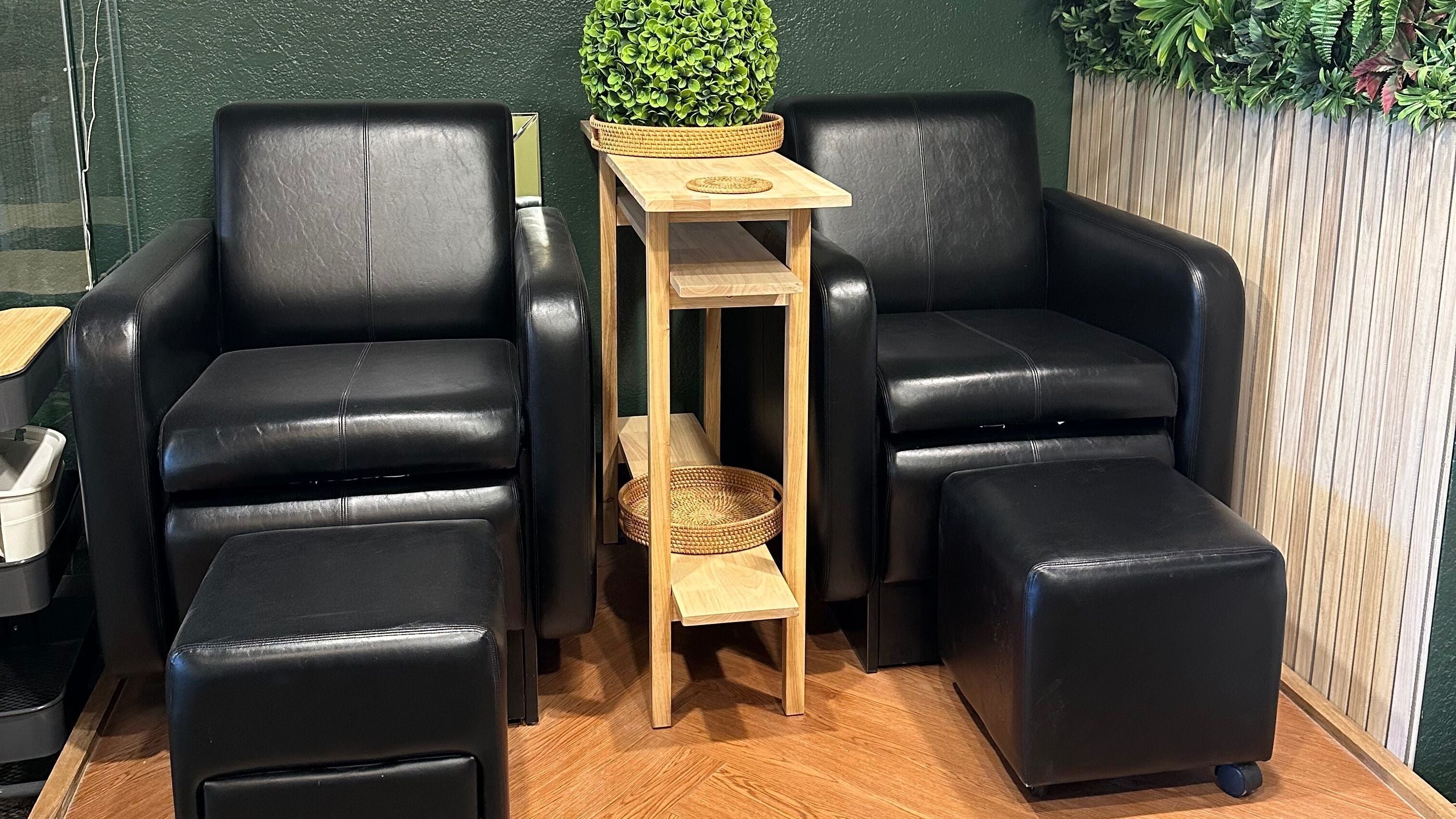 Luxurious seating at Envy Nail Bar, North Lima, Ohio, US, featuring black leather chairs and greenery.