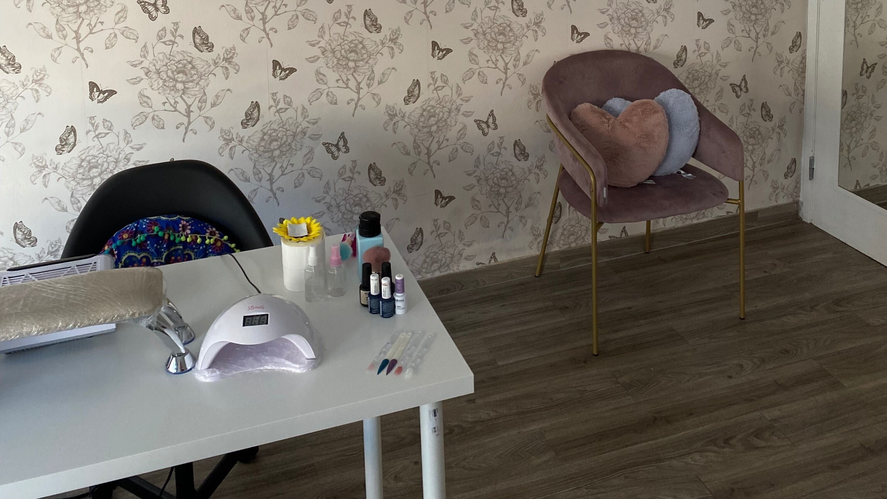 Mesa e cadeiras elegantes no Studio Inês C. Nails, Baixa Da Banheira, PT, com decoração floral e ferramentas de unhas.