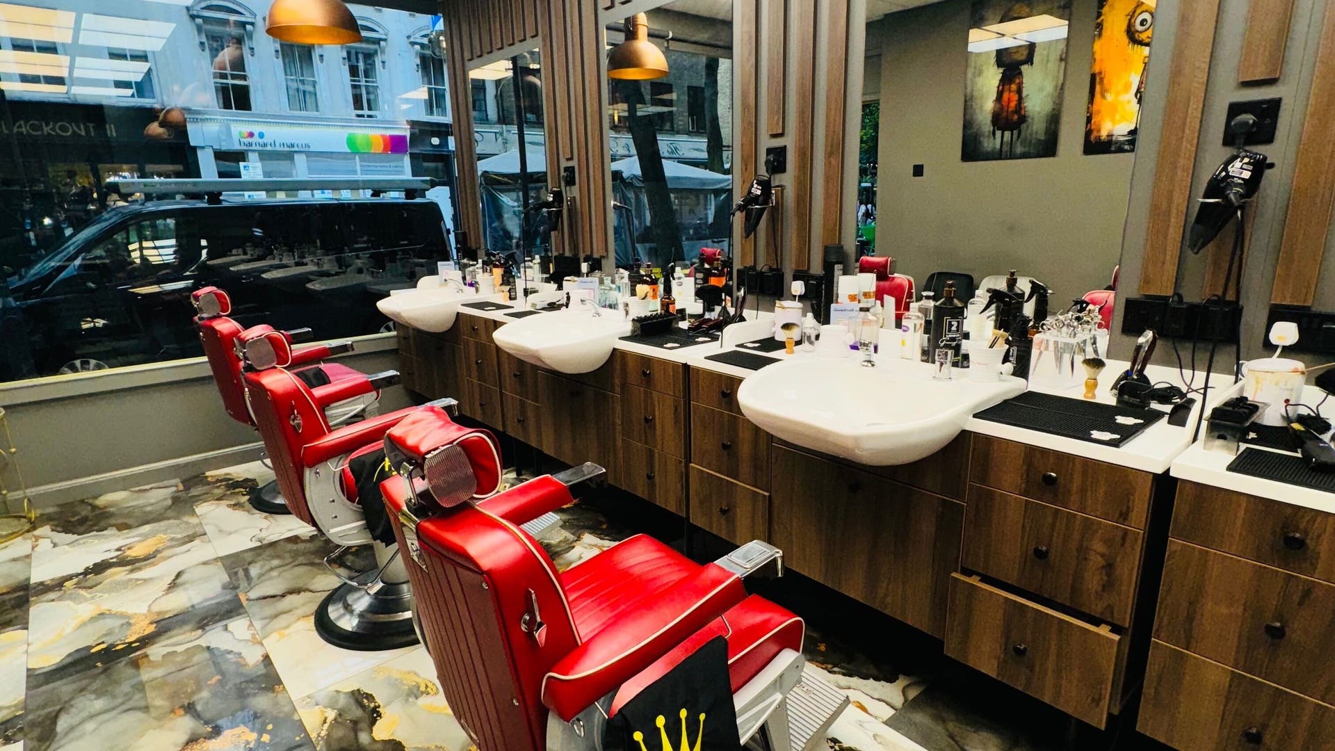 Red barber chairs in stylish 2 Chairs Grooming Room, London, England, GB reflecting modern elegance.