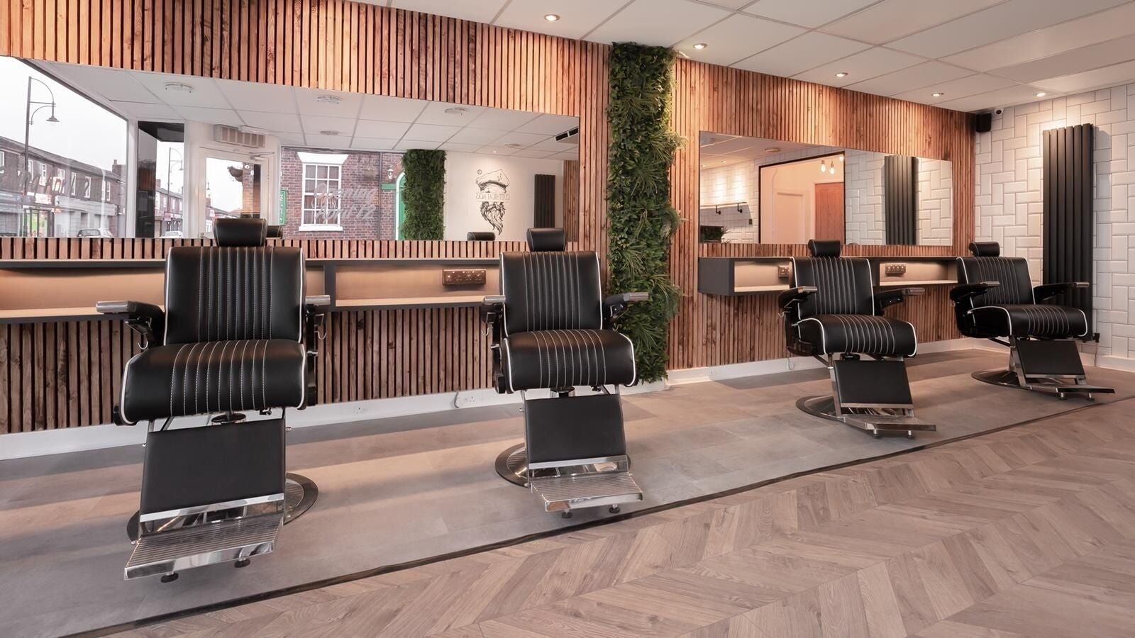 Modern barber chairs at Cutthroat Jacks, Stockport, England, GB, with stylish wood and green decor.