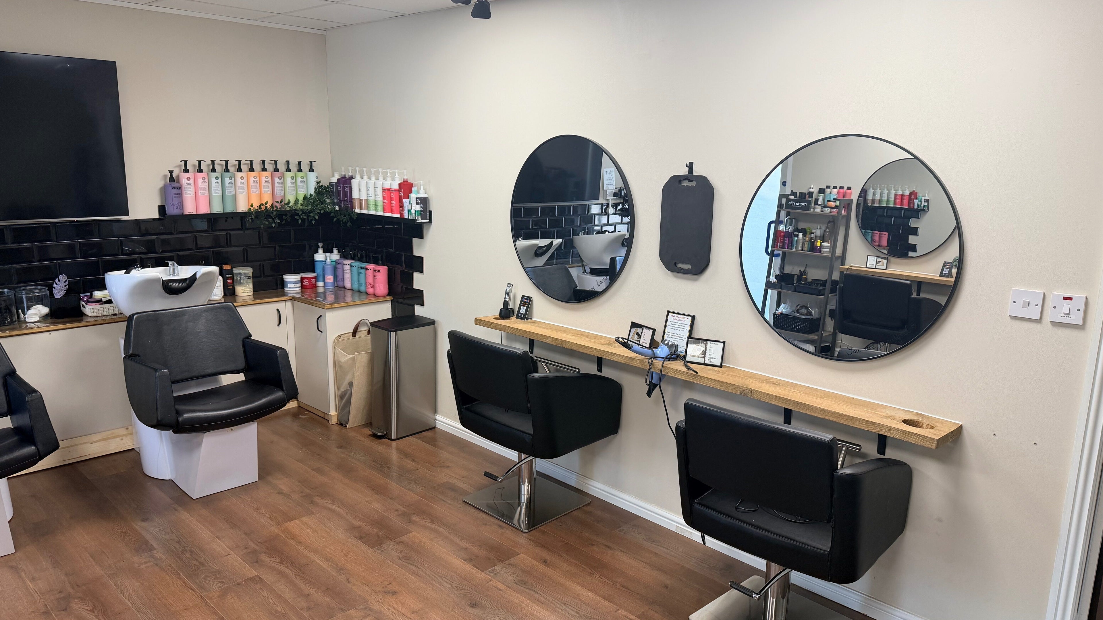 Modern hair salon interior at Elite Hair Salon, Chester, England, GB, featuring sleek chairs and vibrant products.