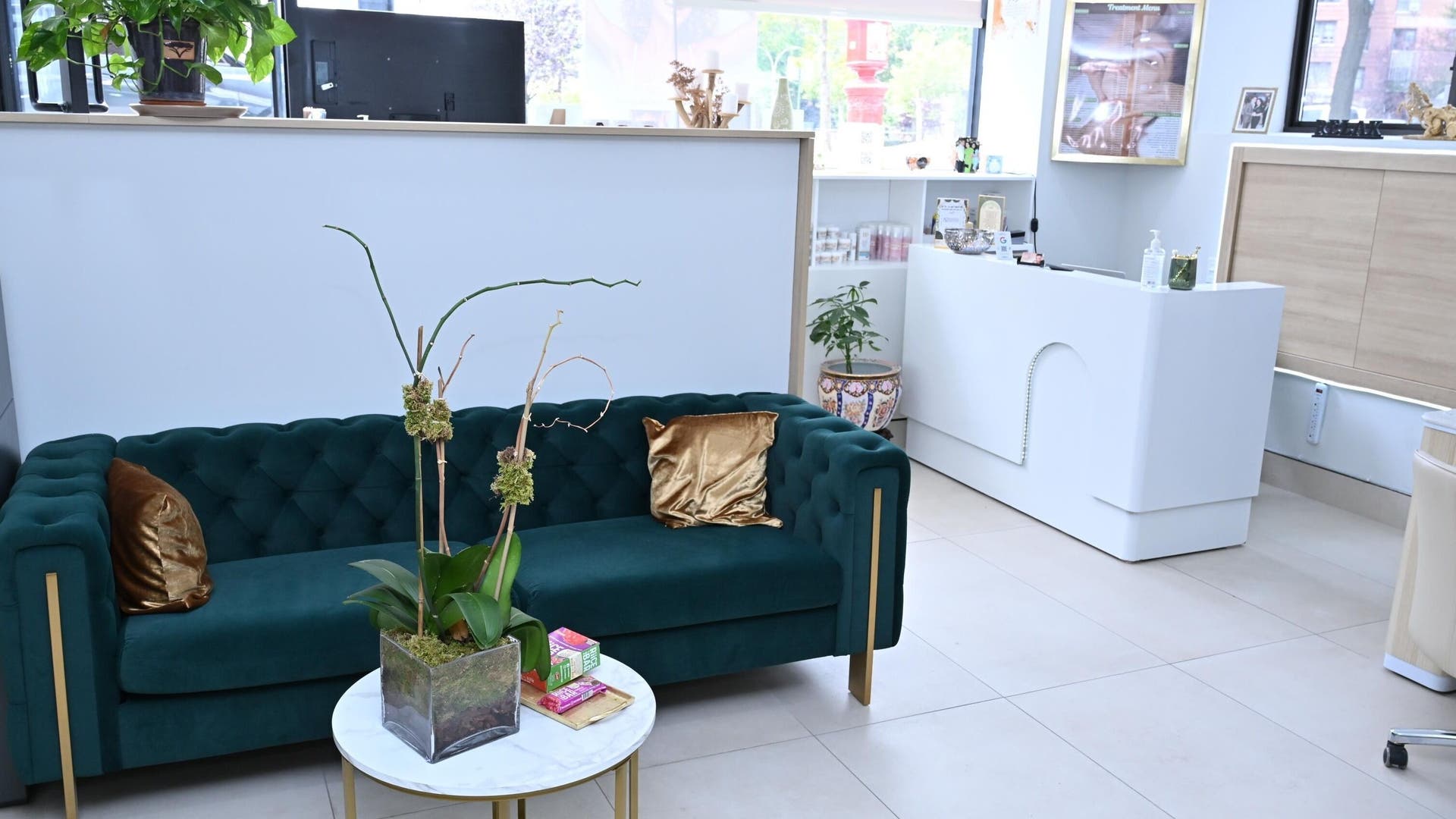 Luxurious lounge area at Laura's Beauty Touch, Rego Park, NY, featuring a green velvet sofa and chic decor.