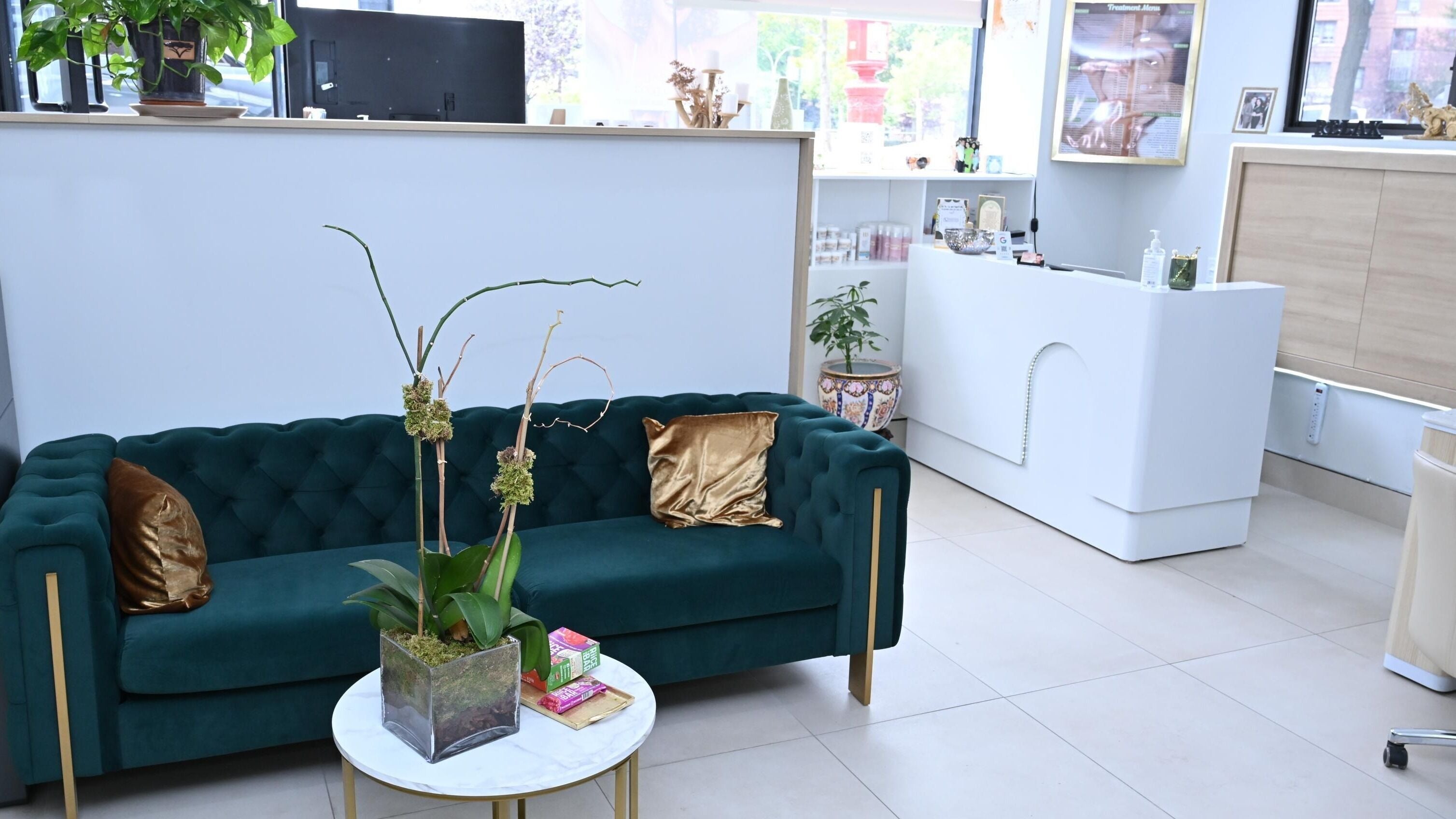 Luxurious lounge area at Laura's Beauty Touch, Rego Park, NY, featuring a green velvet sofa and chic decor.