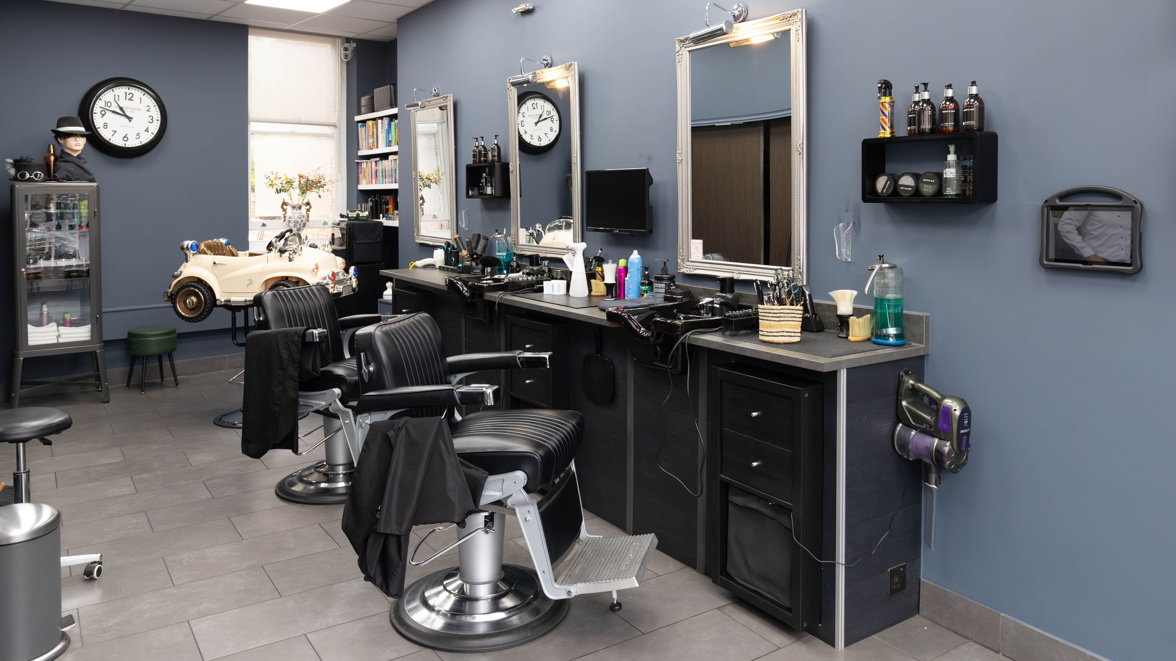 Modern salon interior at The Cut Highgate Village, London, England, GB featuring chic barber chairs and mirrors.