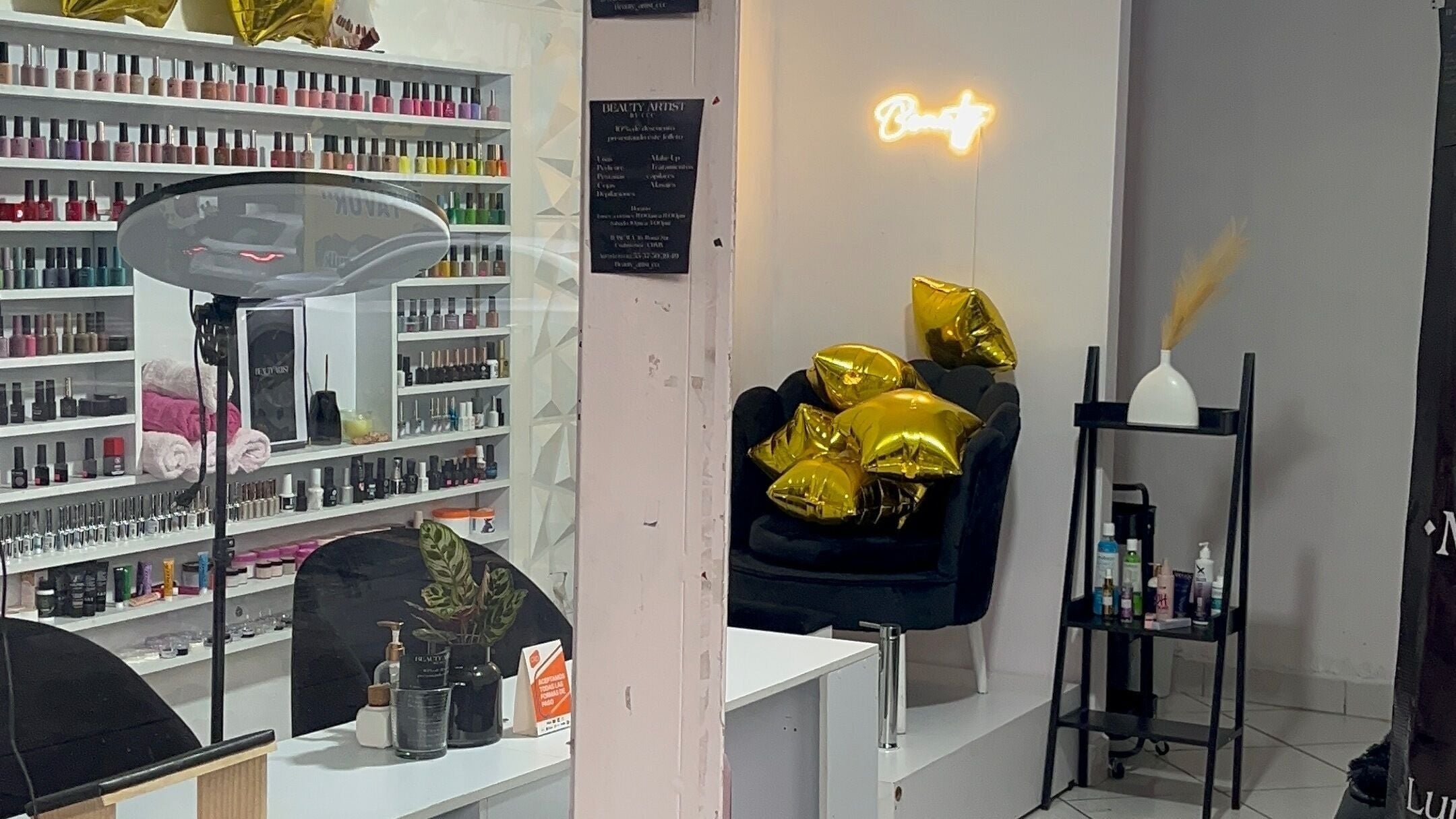 Interior del salón Essence Nails by DRU, Ciudad De México, con esmaltes y sillón decorado con cojines dorados.