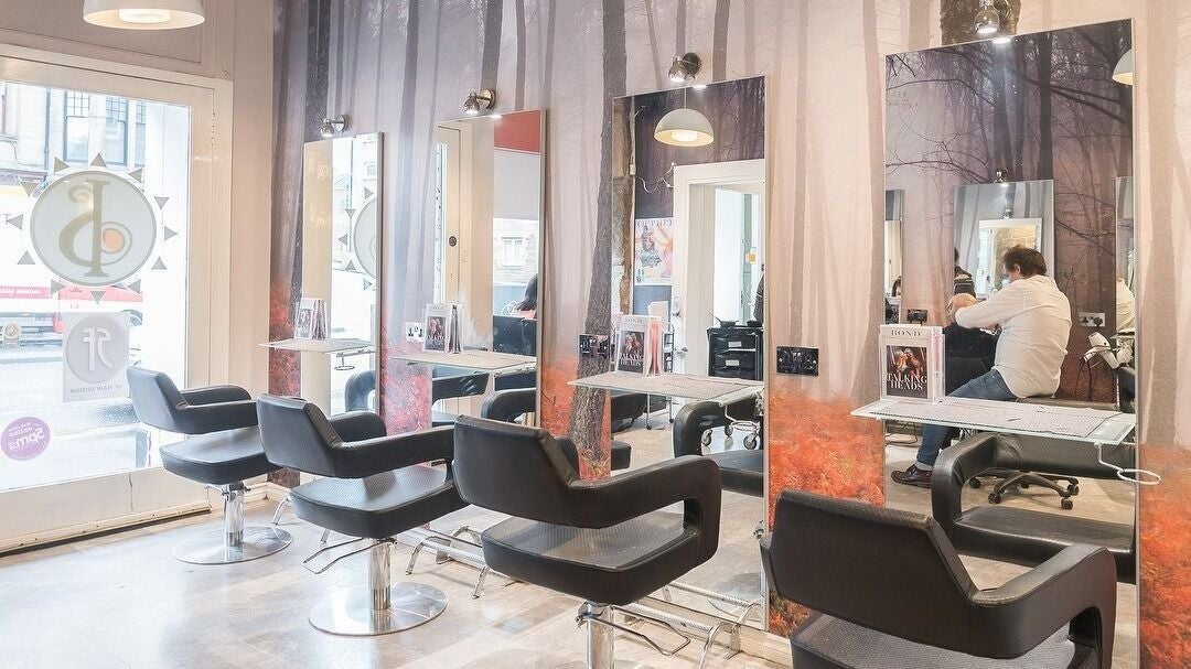 Modern hairdressing station at Iain Stewart Hairdressing Ltd in Paisley, Scotland, GB with stylish chairs and mirrors.