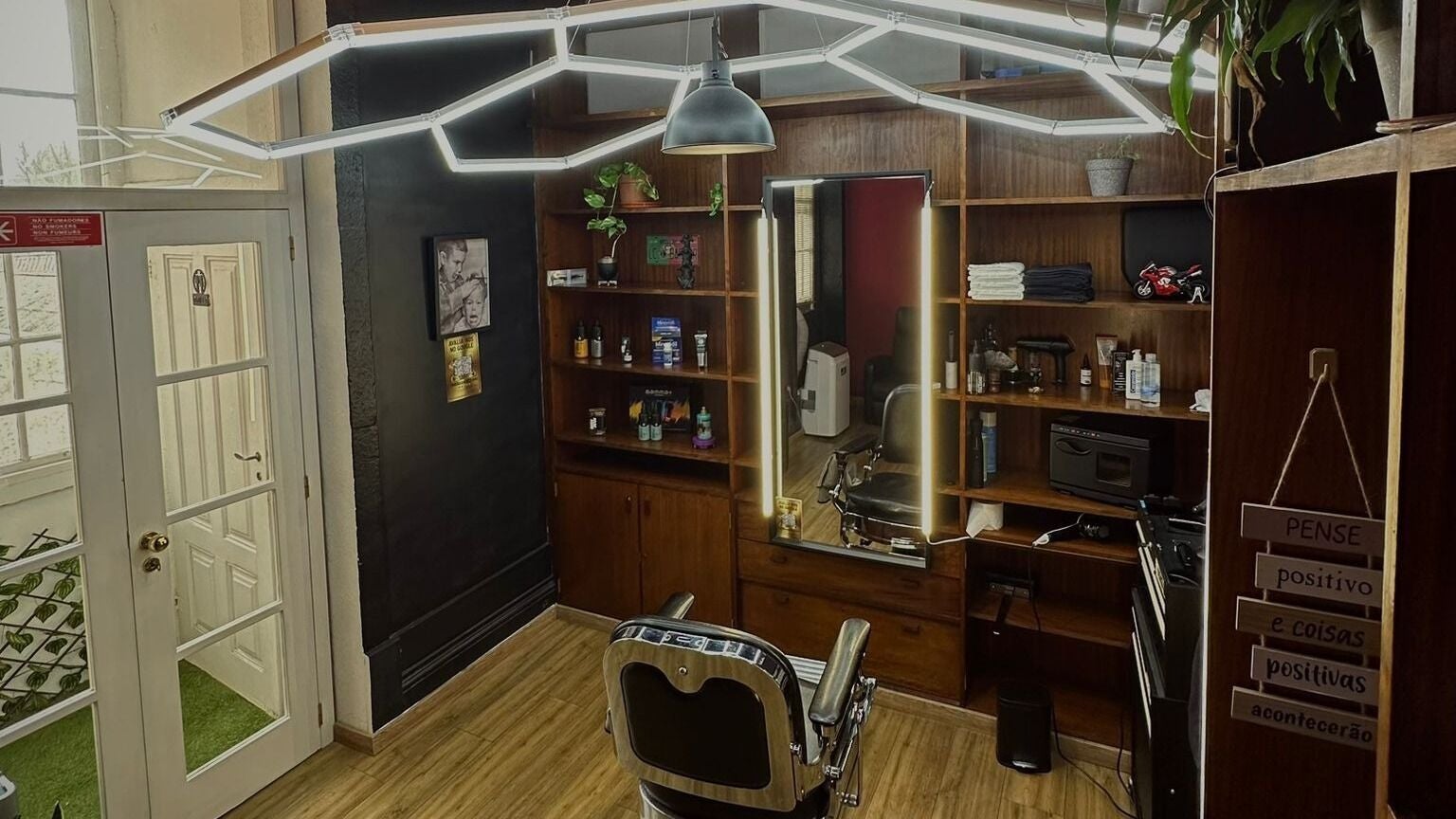Interior moderno de barbearia no ProsBarberStudio, Porto, PT, com decoração em madeira e iluminação estilosa.