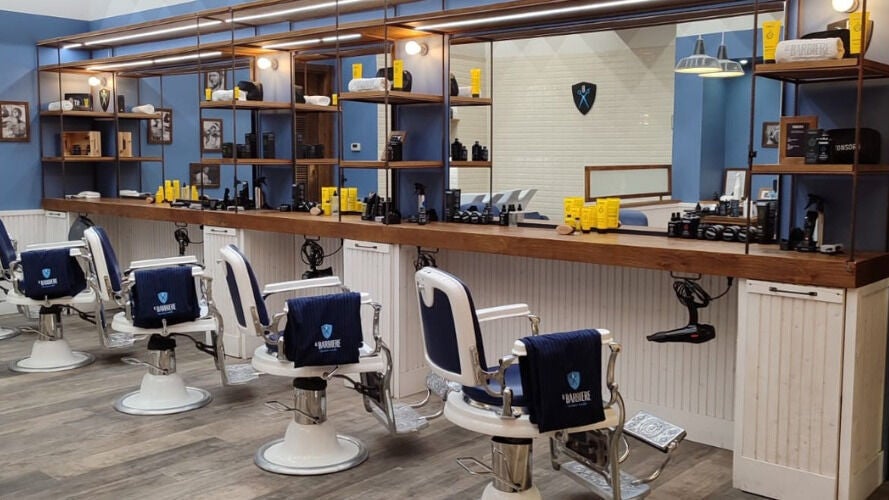 Interno di Il Barbiere Curno, Curno, Lombardia, IT: poltrone vintage e prodotti di bellezza in esposizione.