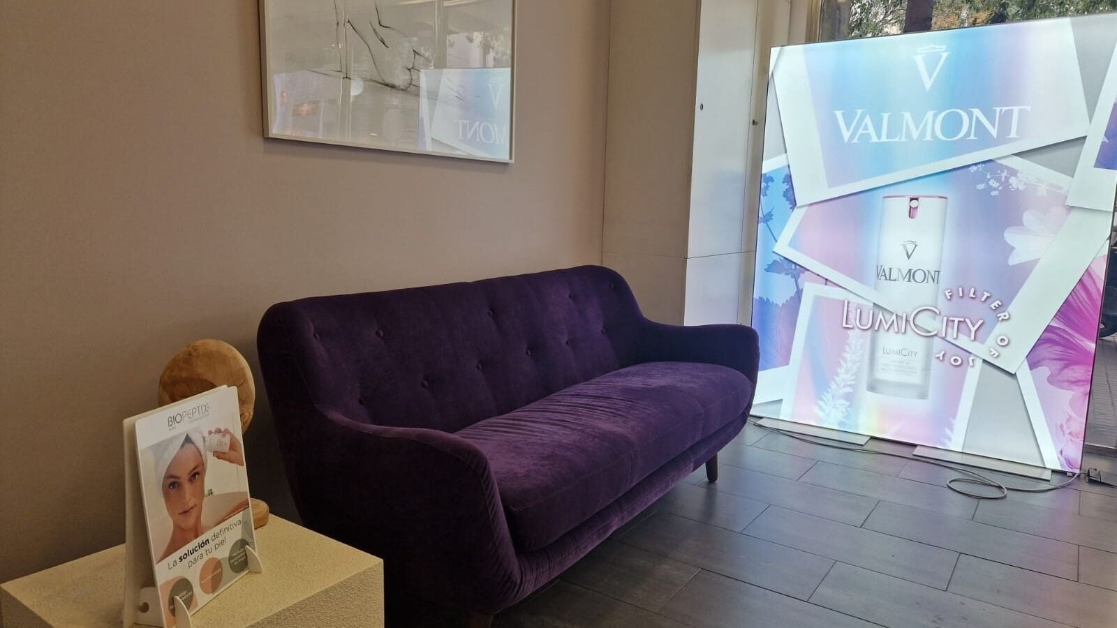 Elegante sofá violeta en Cinc Estètica, Barcelona, Catalunya, ES, con cartel publicitario de Valmont.