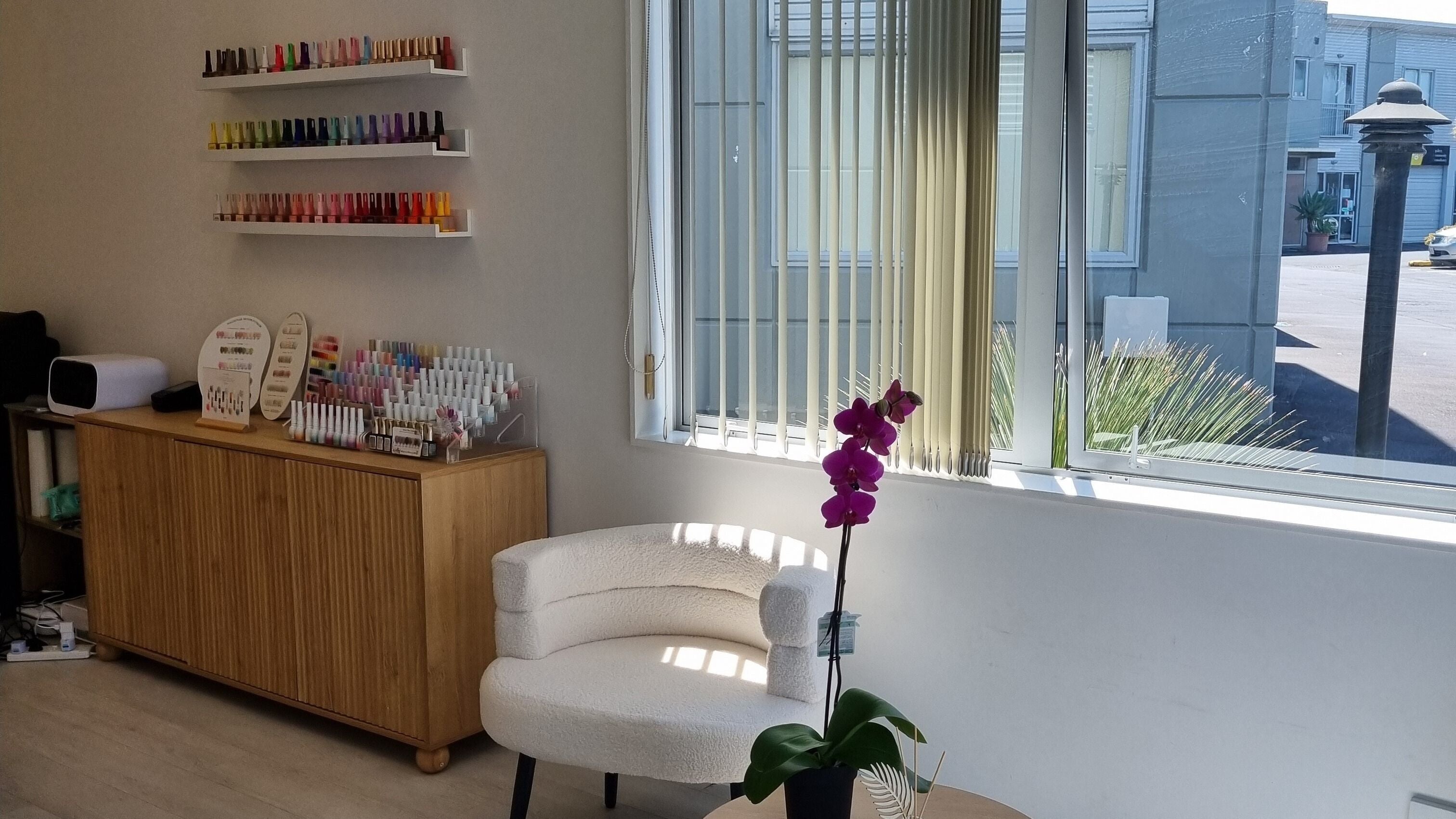 JuJu beauty studio in Auckland, NZ featuring a vibrant nail polish display and cozy seating by the window.