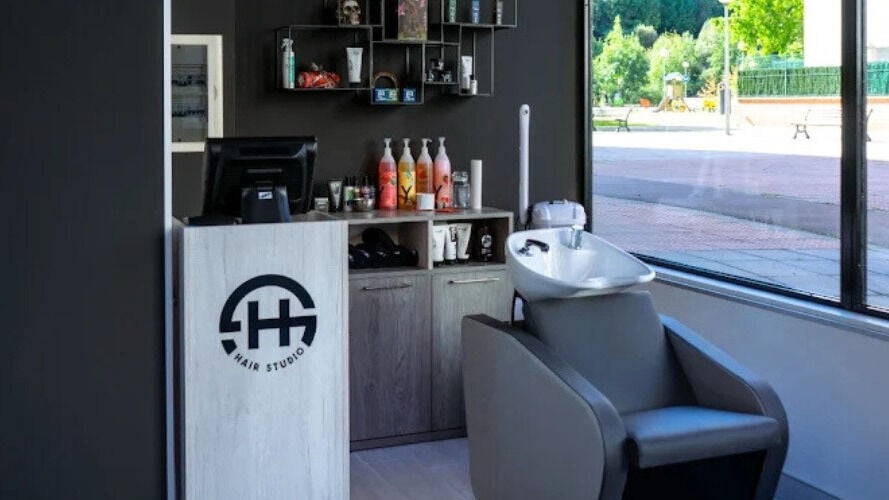 Recepción moderna en H HAIR STUDIO, Baracaldo, País Vasco, ES, destacando el lavacabezas y productos de belleza.