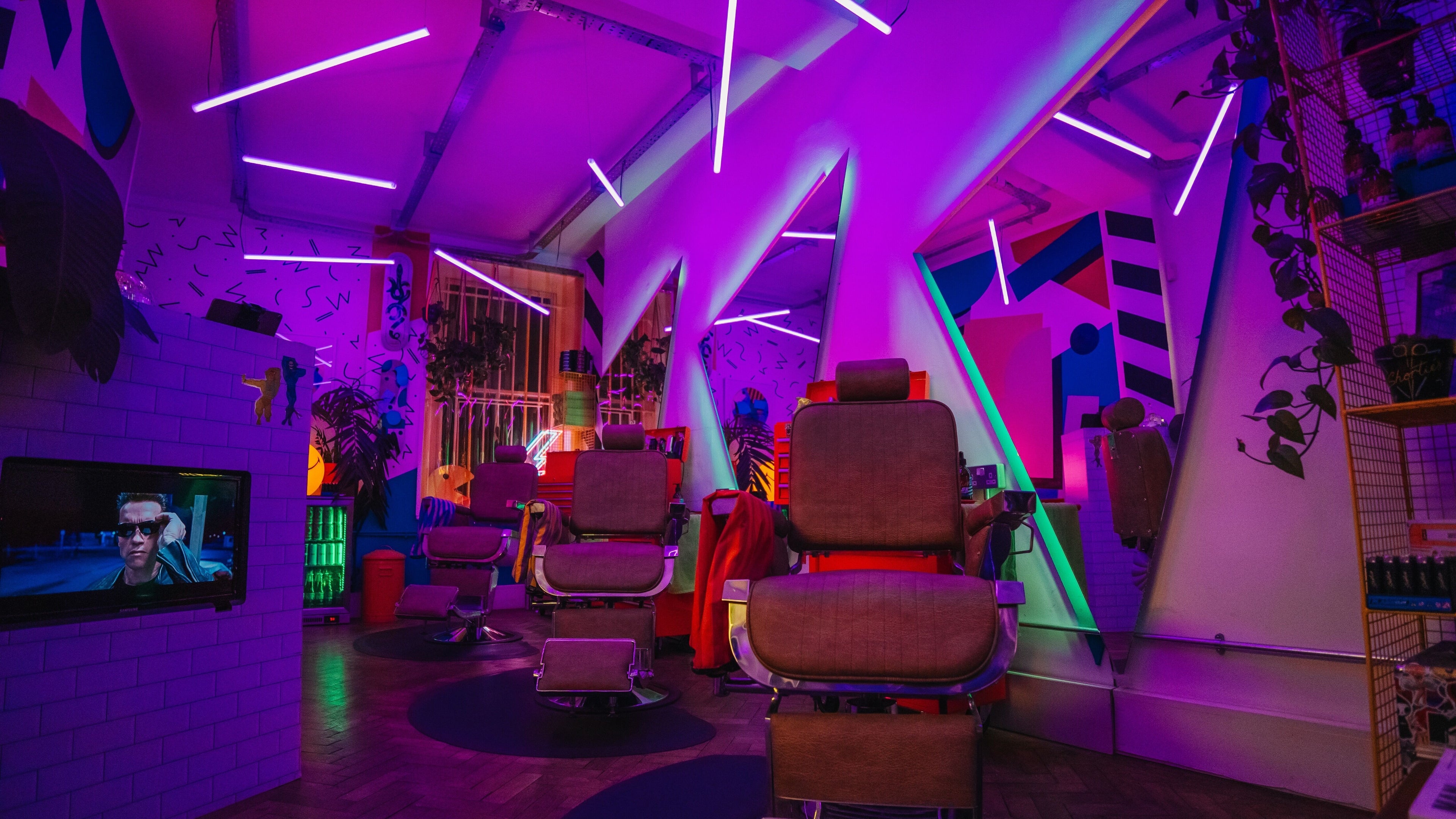 Vibrant neon-lit interior of Shorties in London, England, GB with stylish barber chairs and modern decor.