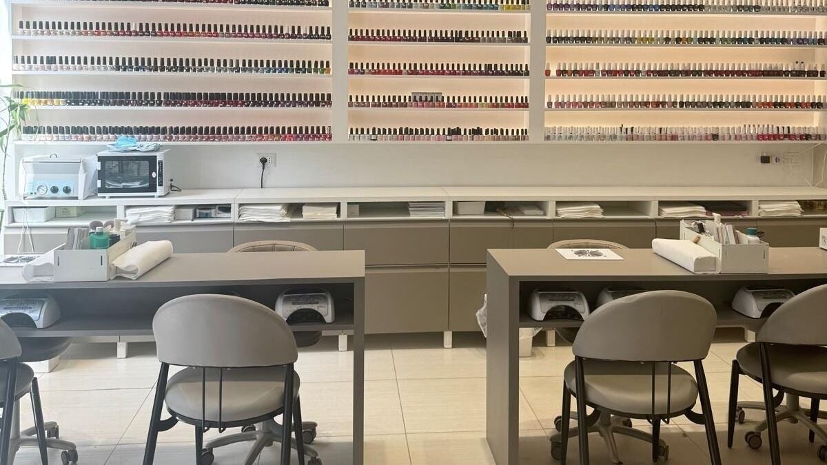Interno del salone Nail Care a Milano, Lombardia. Elegante esposizione di smalti e postazioni di lavoro moderne per la manicure.