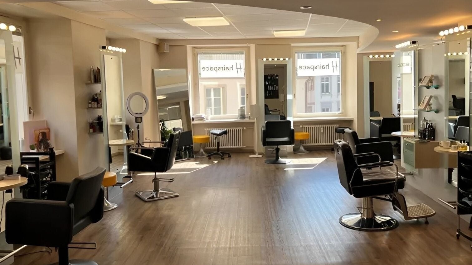 Innenansicht von Ronny the Barber in Basel, Basel-stadt, CH, mit eleganten Friseurstühlen und Spiegeln.
