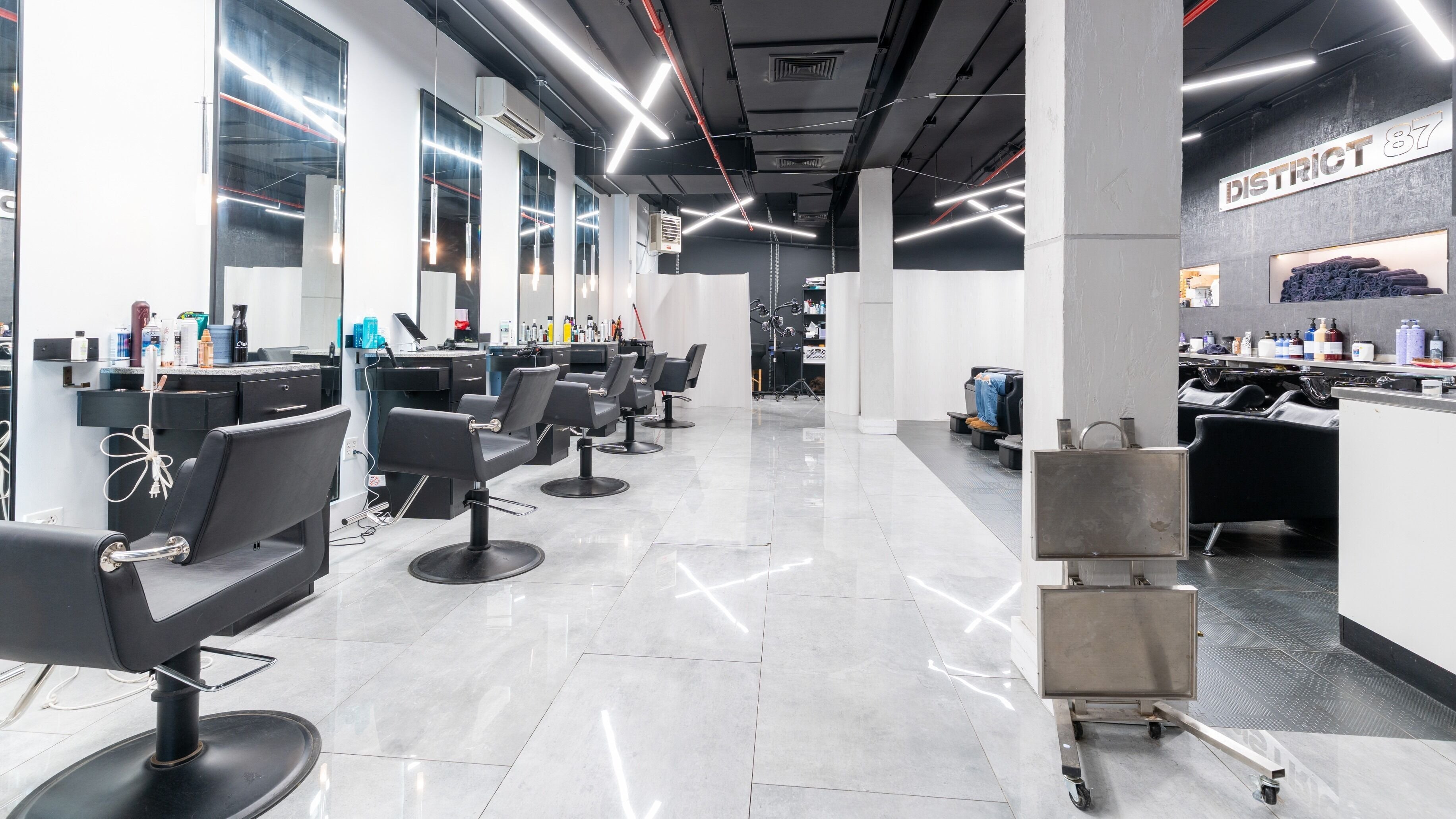 Modern interior of District 87 Salon in New York, NY, US, featuring sleek styling chairs and mirrors.