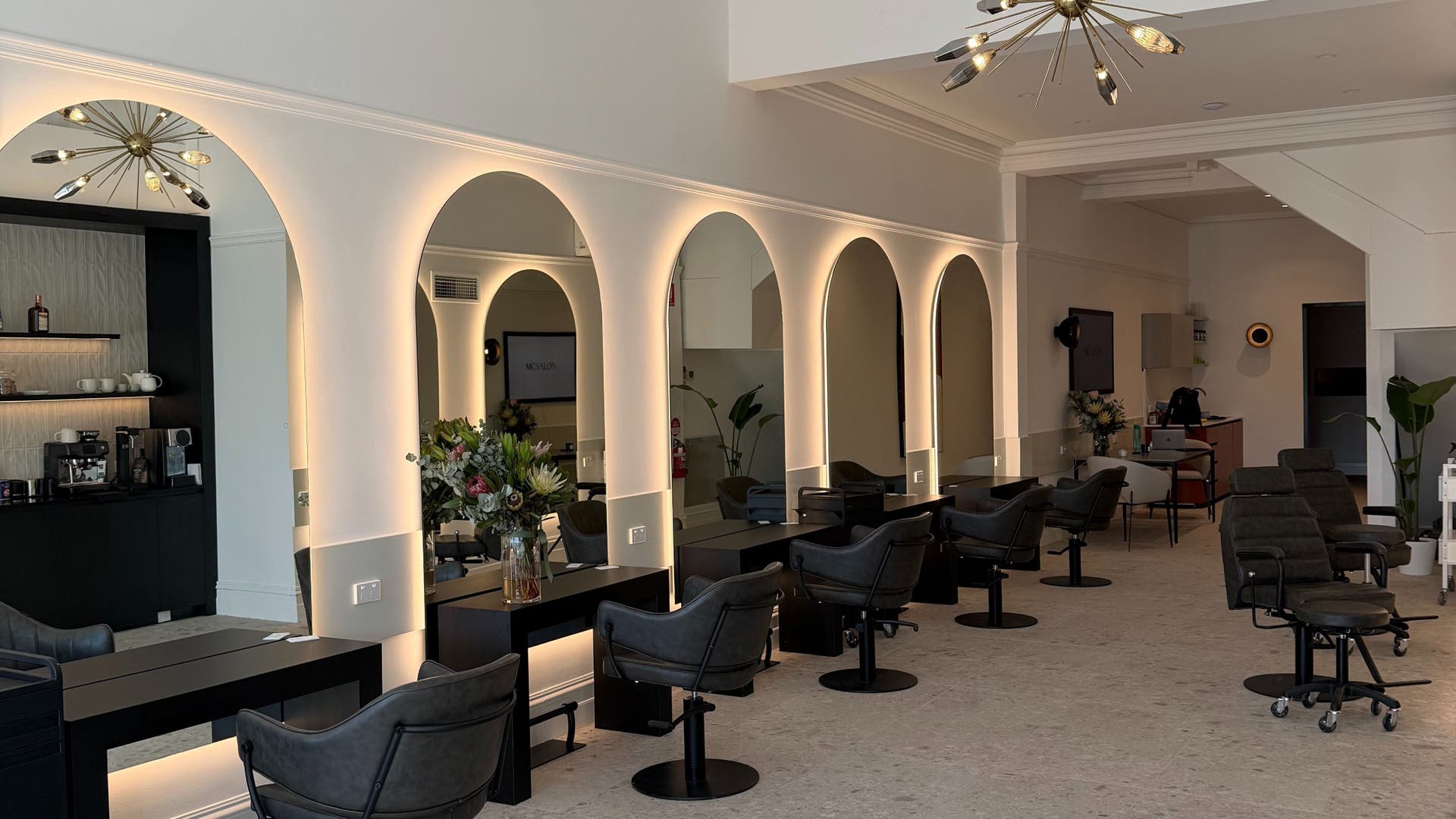 Stylish interior of MC SALON, Malvern, Victoria, AU with modern salon chairs and illuminated mirrors.