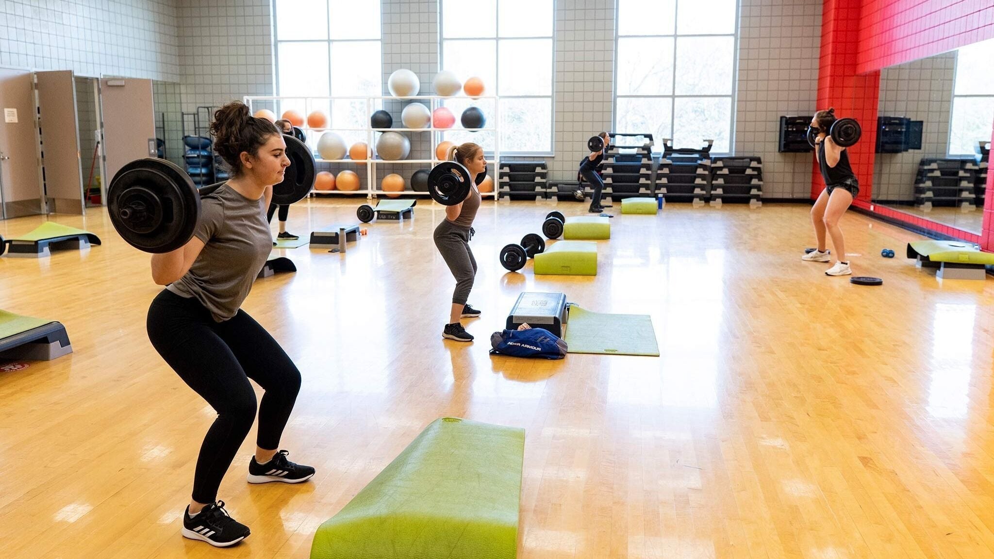 People lifting weights in a fitness studio at New York, New York, US, promoting health and wellness.