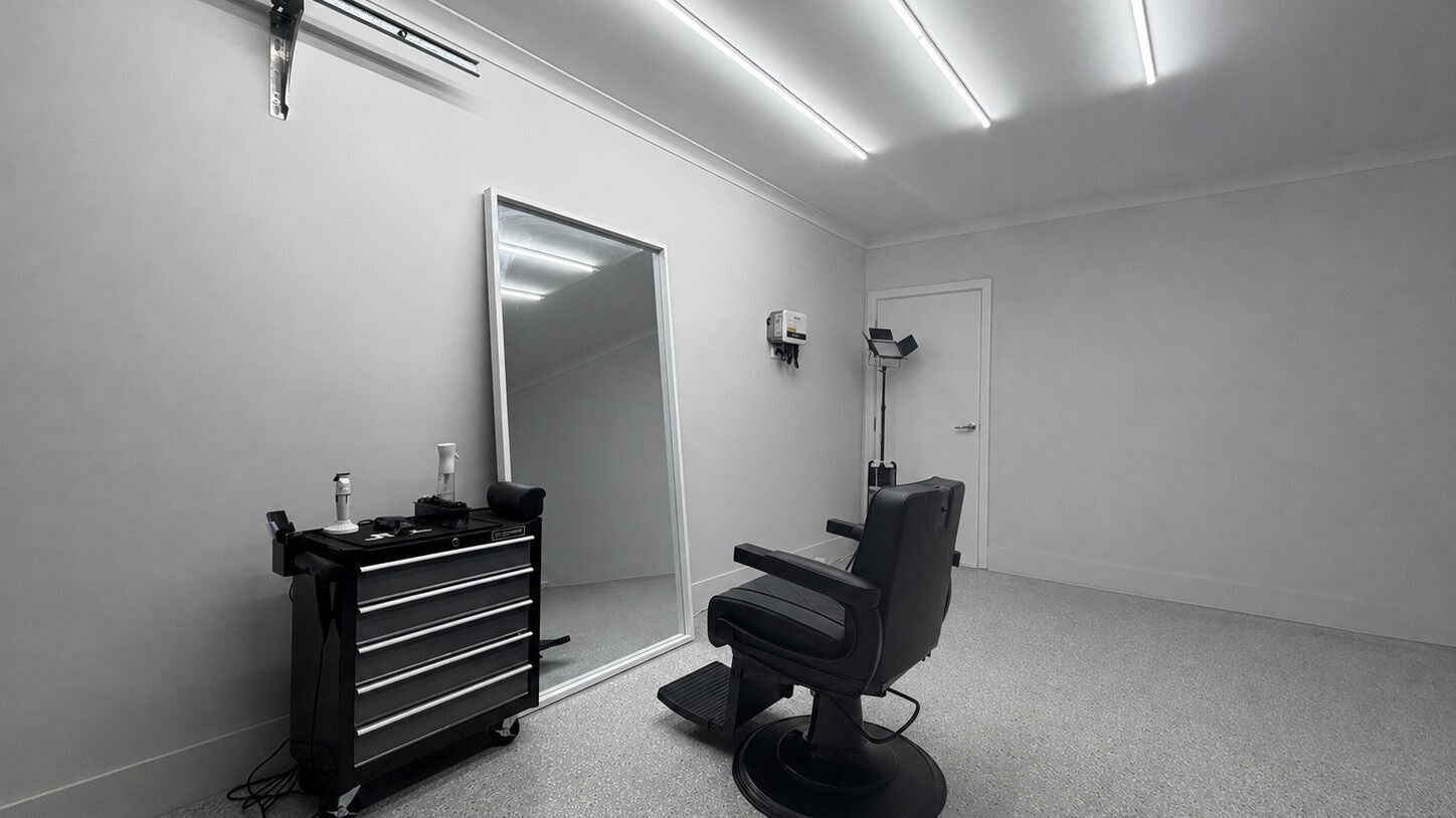 Modern barber chair and mirror setup at SheBarbers, Melbourne, Victoria, AU, showcasing sleek design.