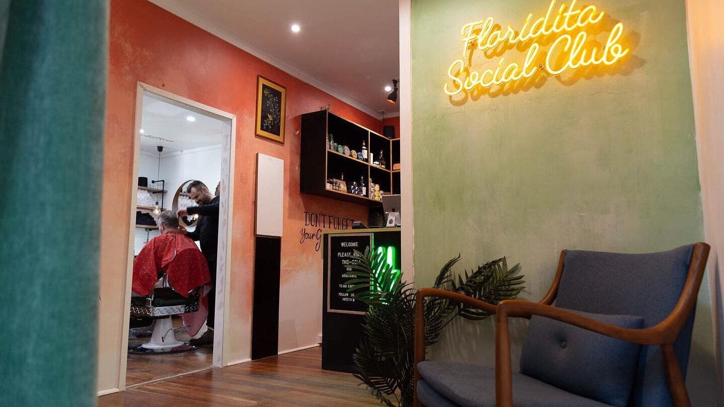 Empire Barbering Company in Ashgrove, QLD. Cozy interior with a stylist and client in focus.